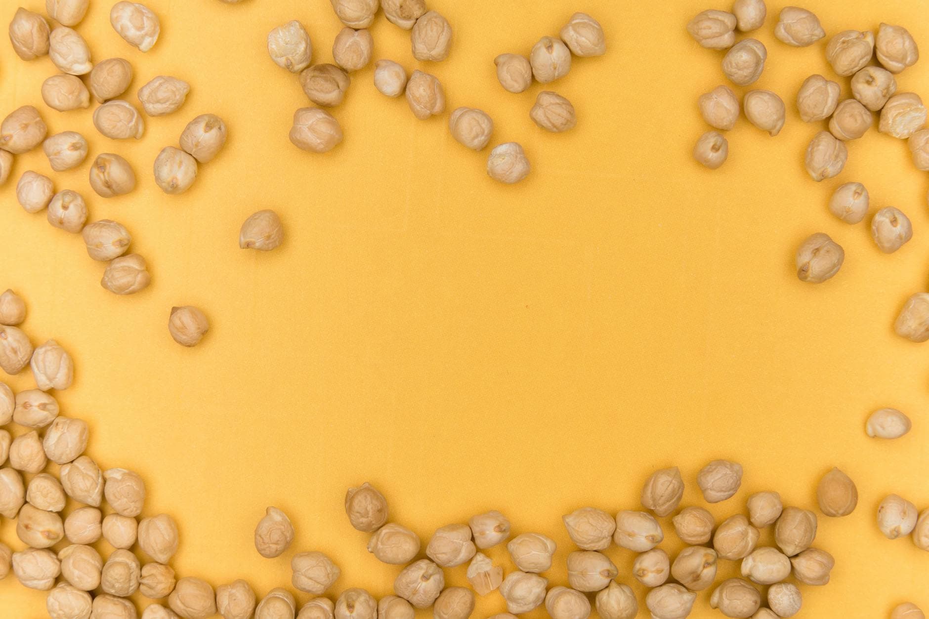 A close-up of chickpeas scattered on a vibrant yellow background, showcasing healthy legumes. - iron protein foods