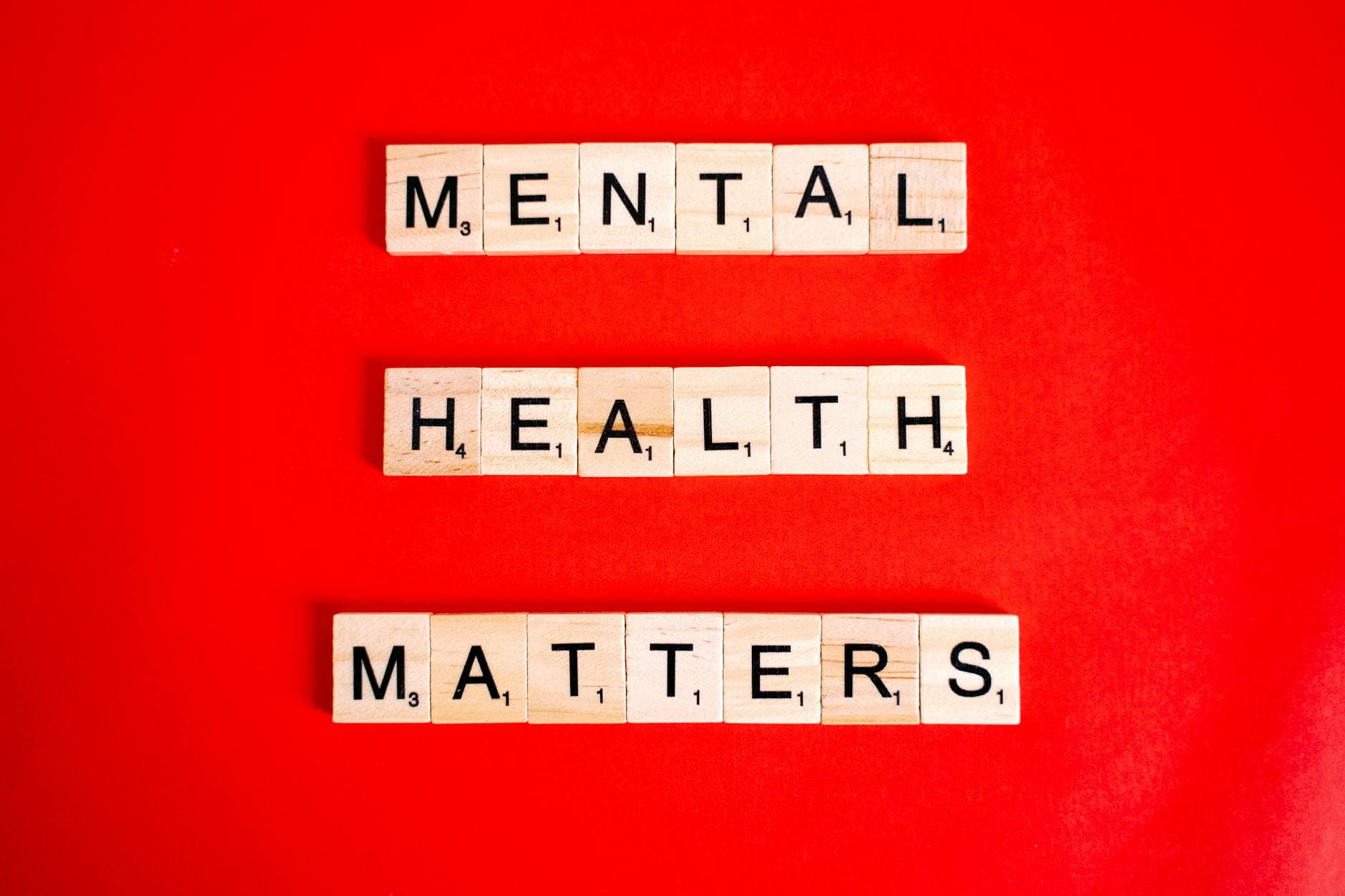 Wooden tiles spelling 'Mental Health Matters' on a vivid red background. - mental wellness practices