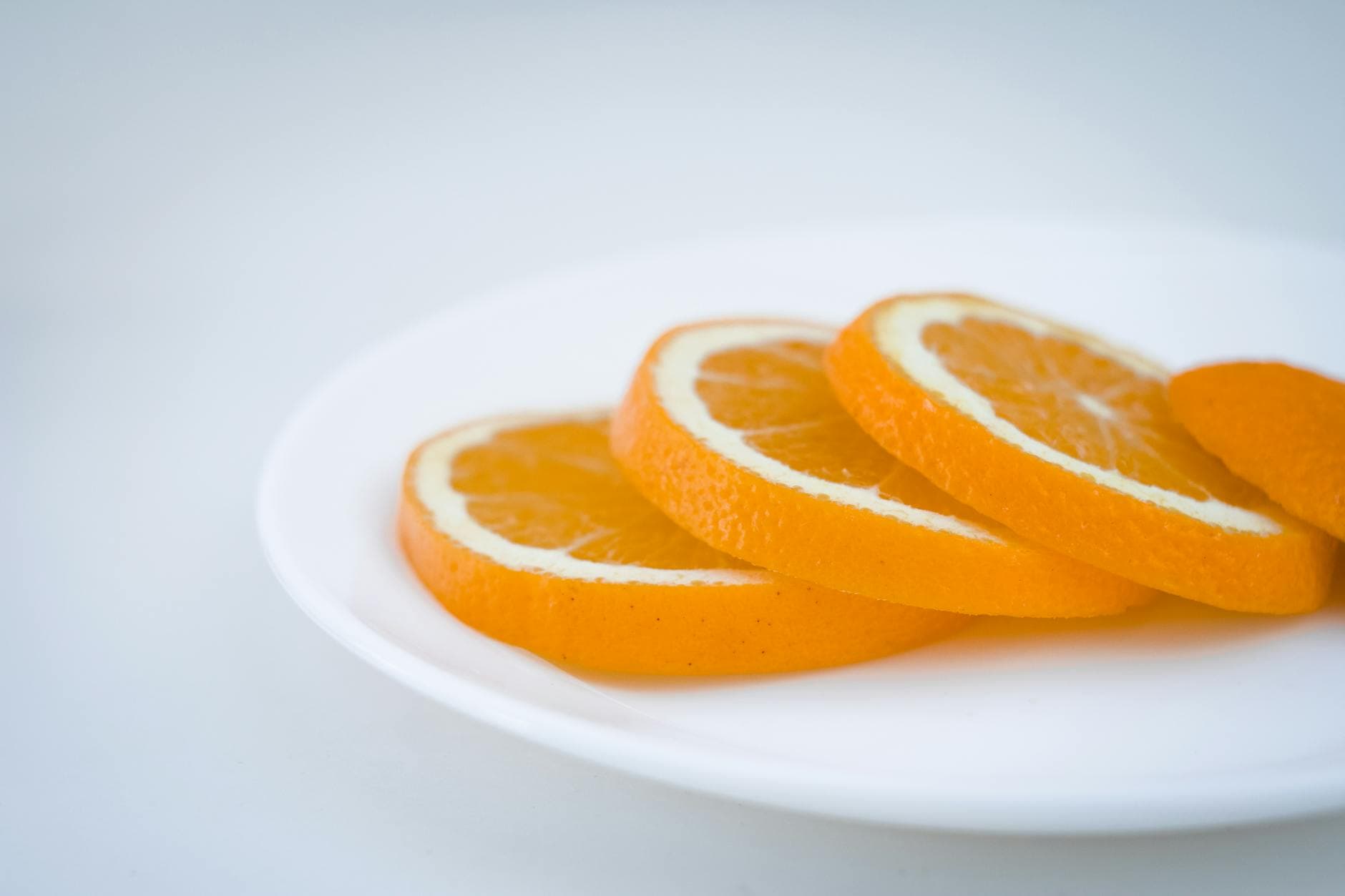 Close-up of fresh orange slices beautifully arranged on a white plate in a studio setting. - natural immune support
