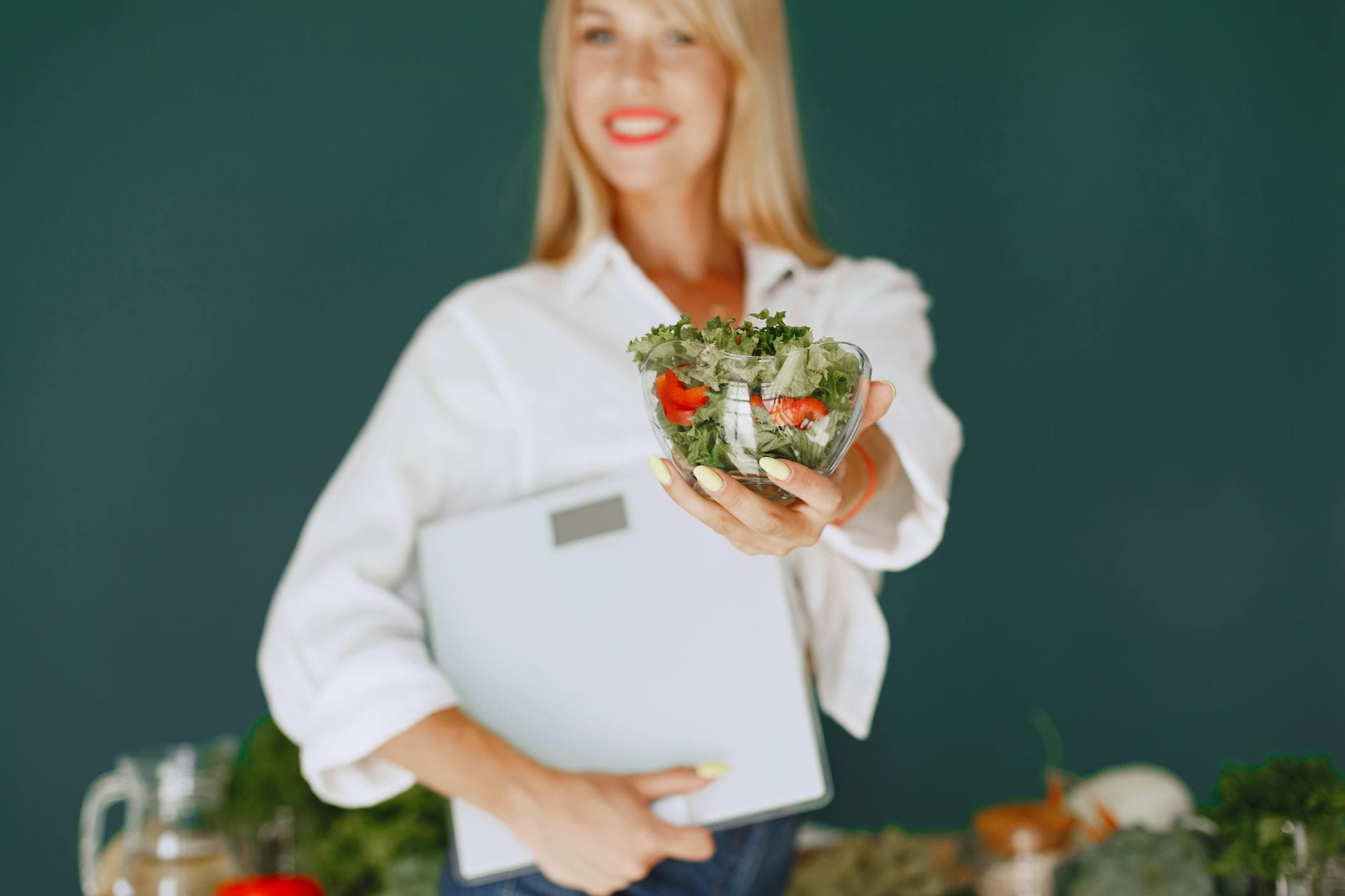 A woman with a vibrant smile offering a fresh salad bowl, promoting healthy eating. - teen weight loss