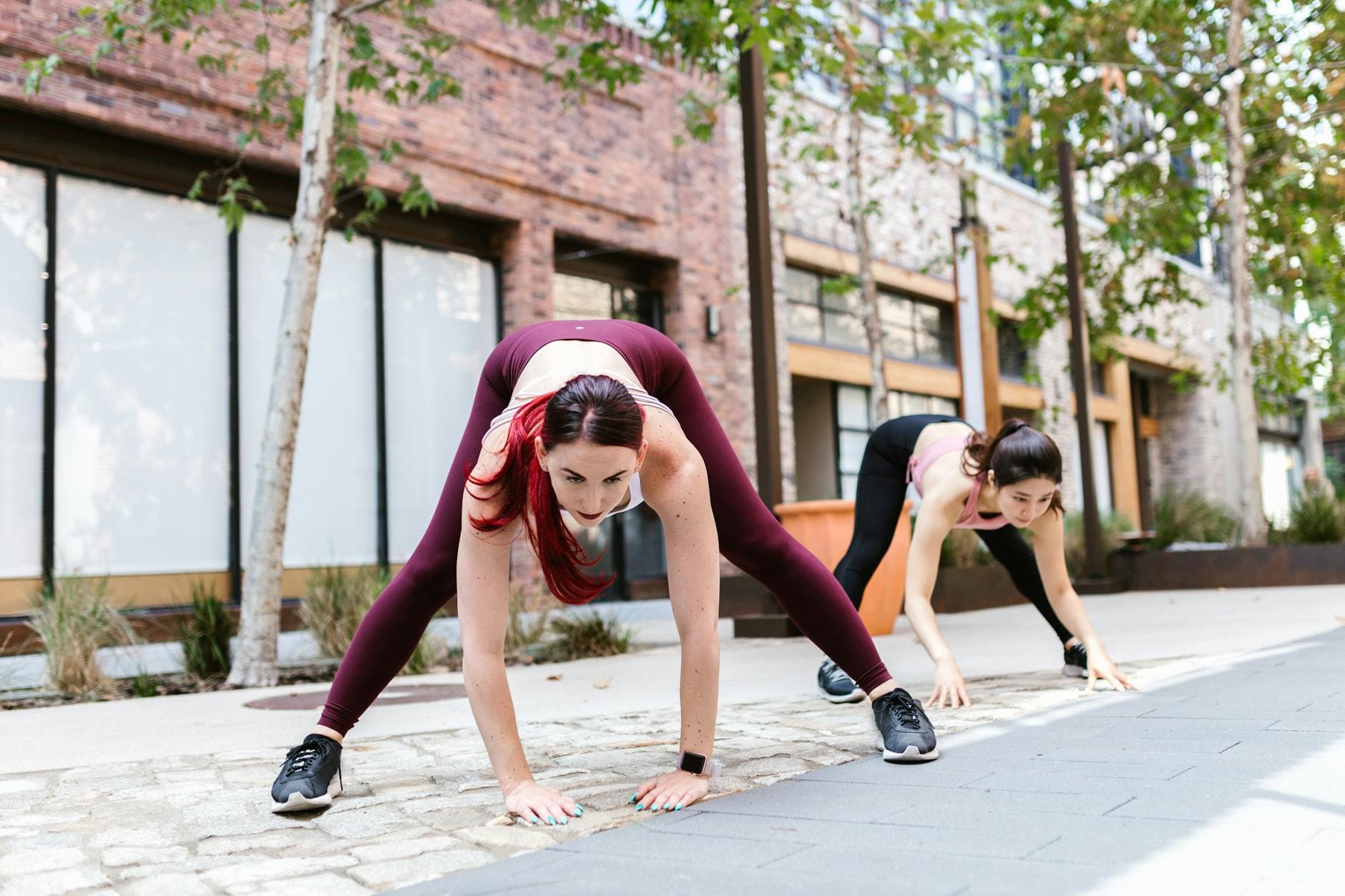 Two women performing dynamic stretches outdoors, showcasing fitness and strength. - beginner workouts
