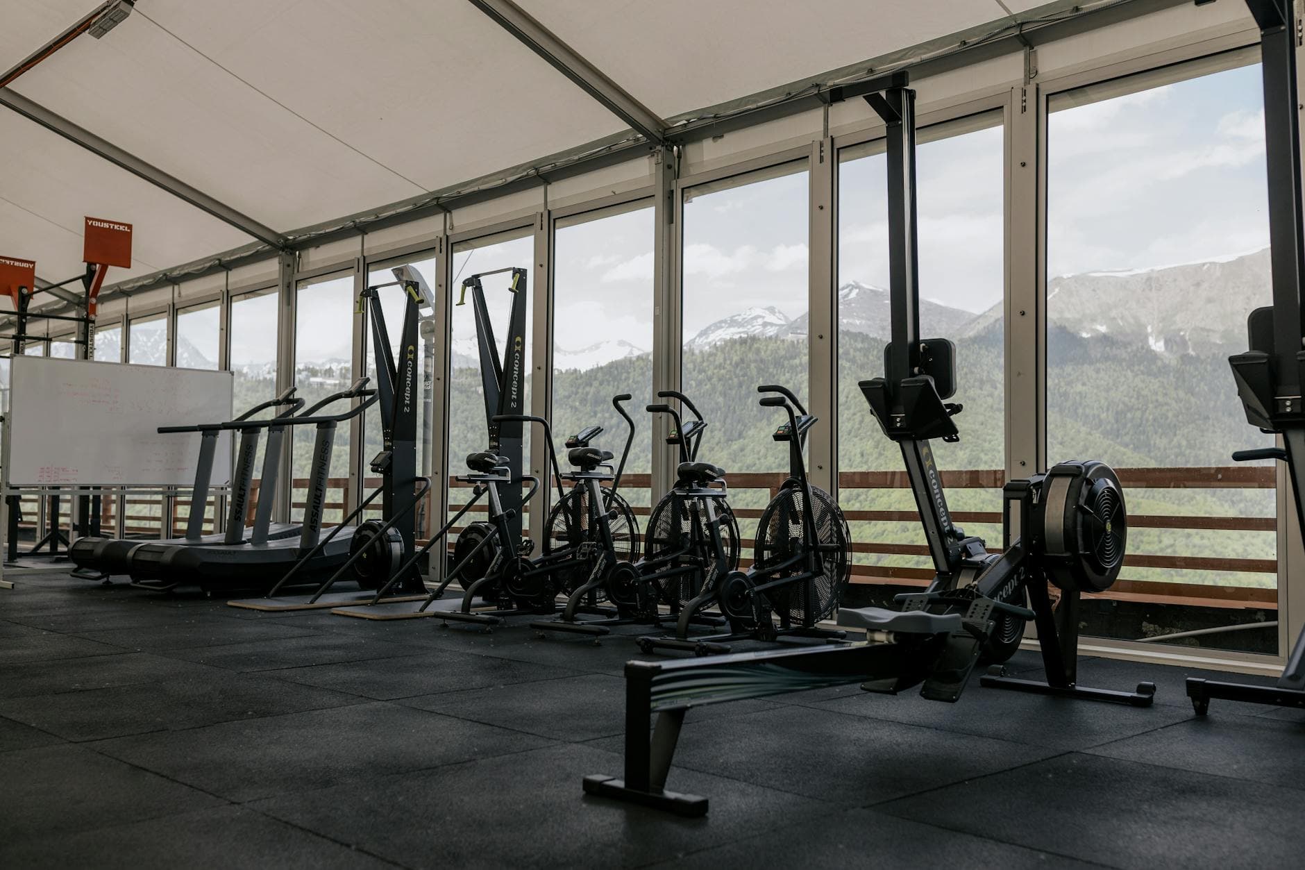 Spacious indoor gym featuring state-of-the-art equipment with scenic mountain views outside large windows. - gym cardio machines