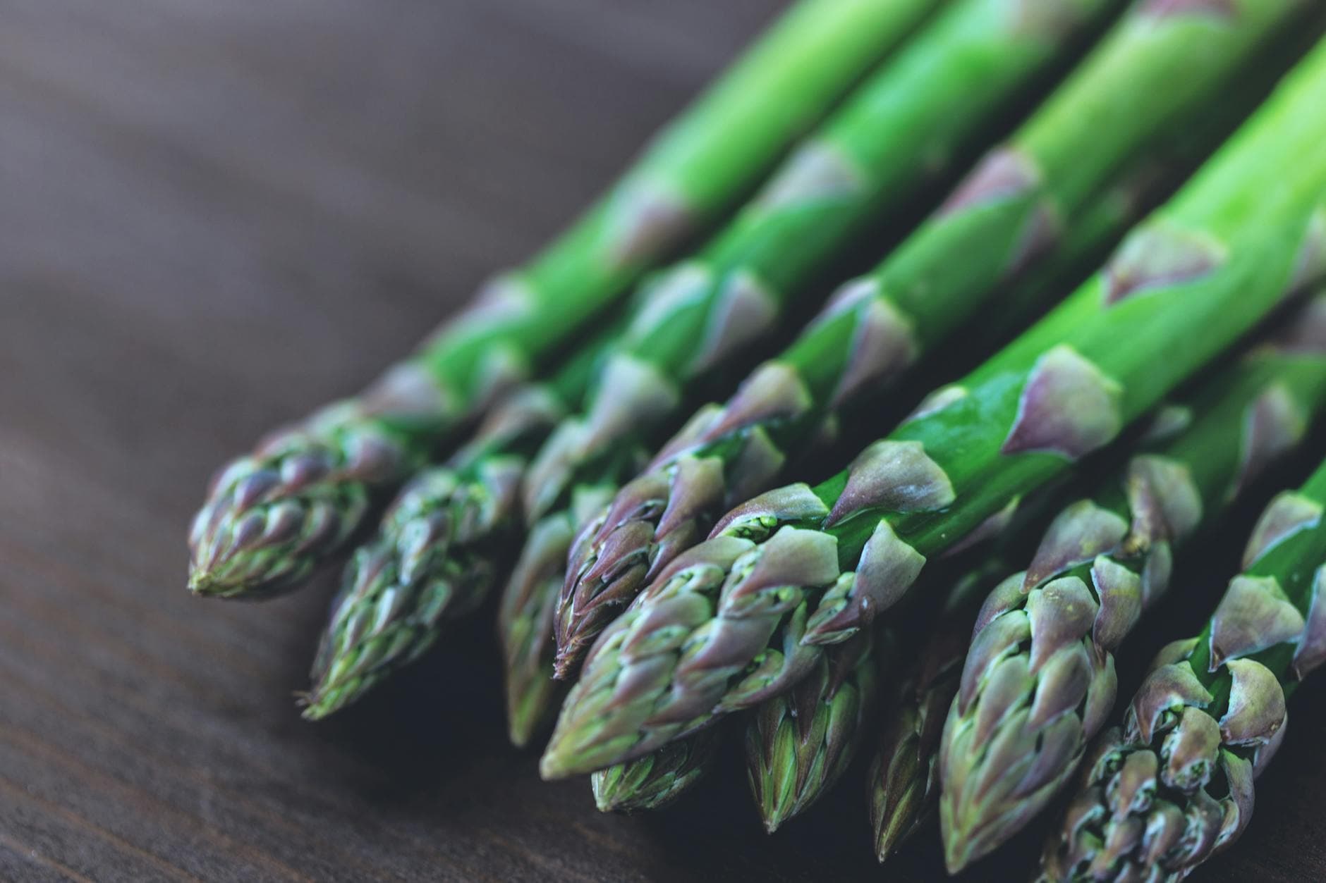 Close-up of fresh green asparagus spears displayed on a rustic wooden table. - spring energy foods