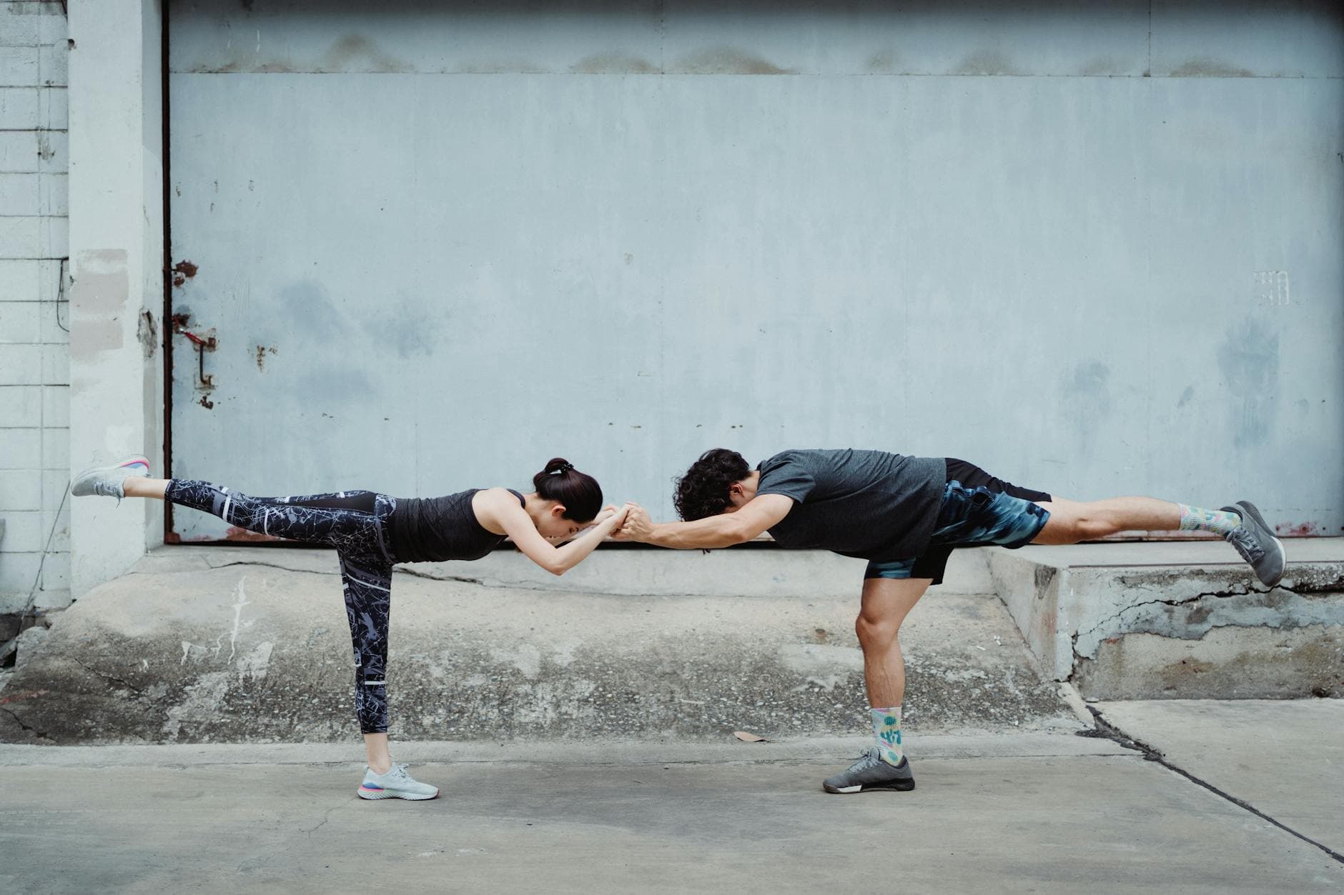 A man and woman practicing balance exercises on one leg in an urban environment. - balance exercise social life