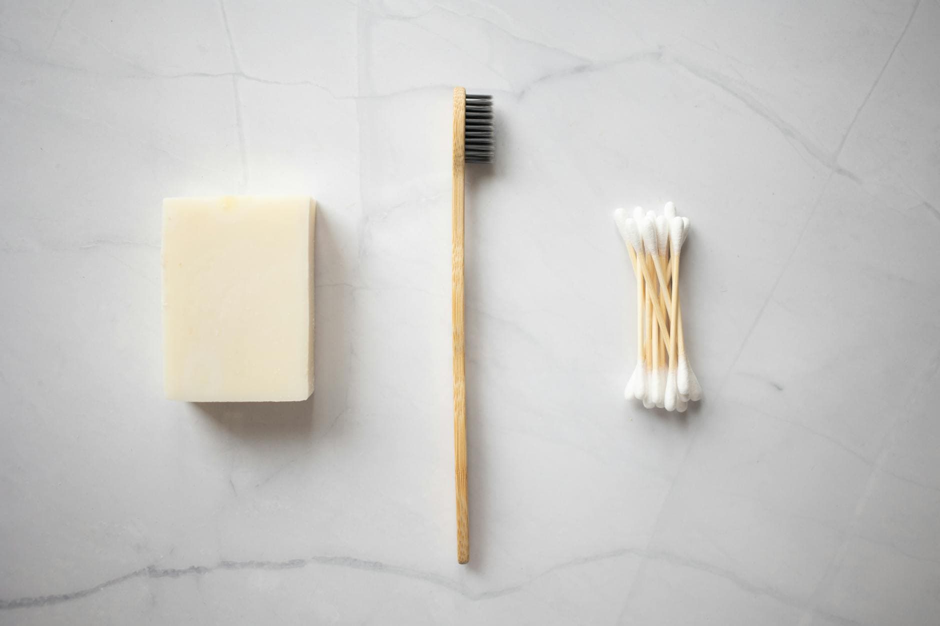 From above of bamboo toothbrush placed between organic soap and wooden ear sticks placed on marble table - personal hygiene tips