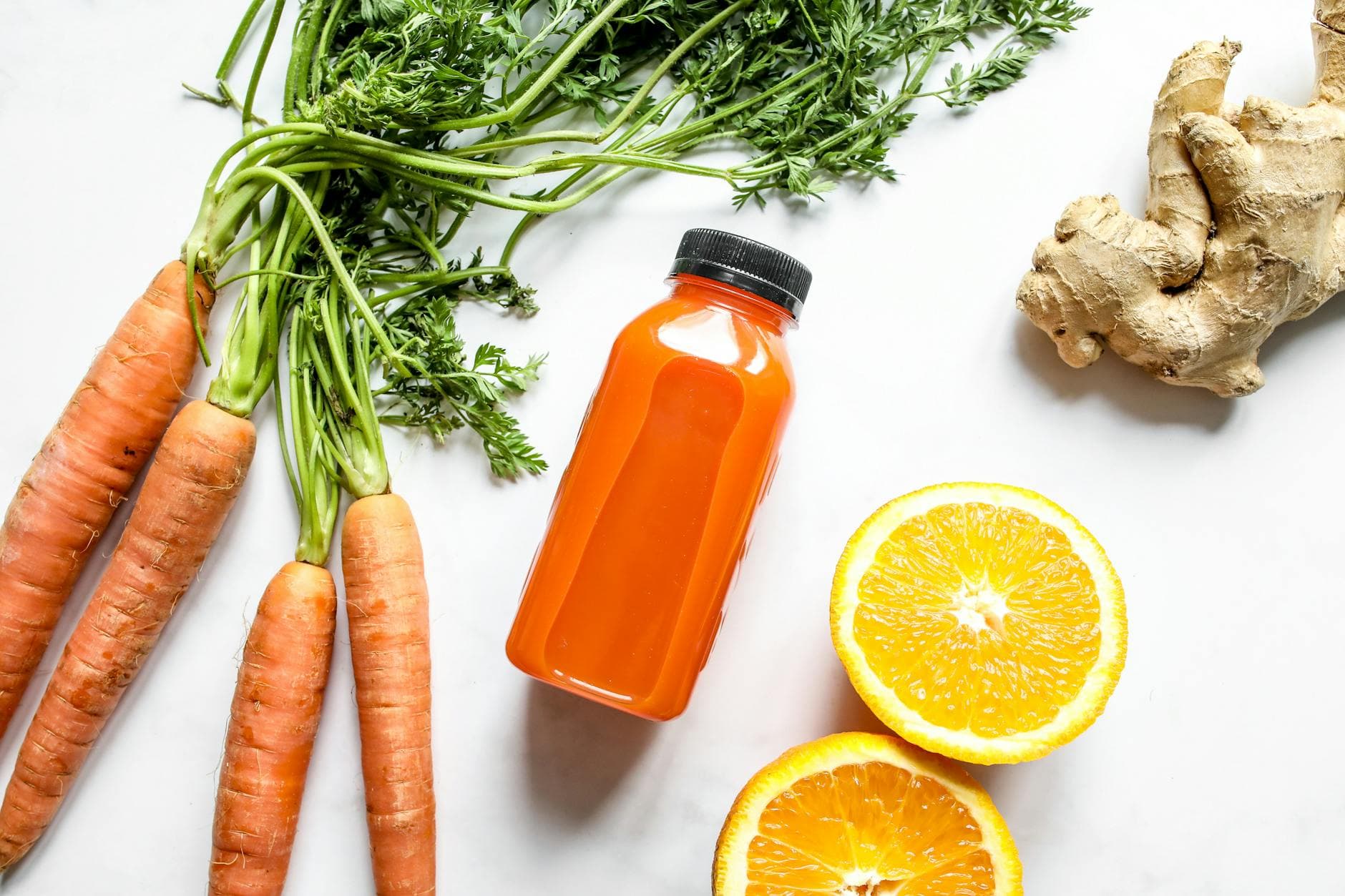 Top view of fresh carrot and orange juice with ginger on a white background. - spring detox plan