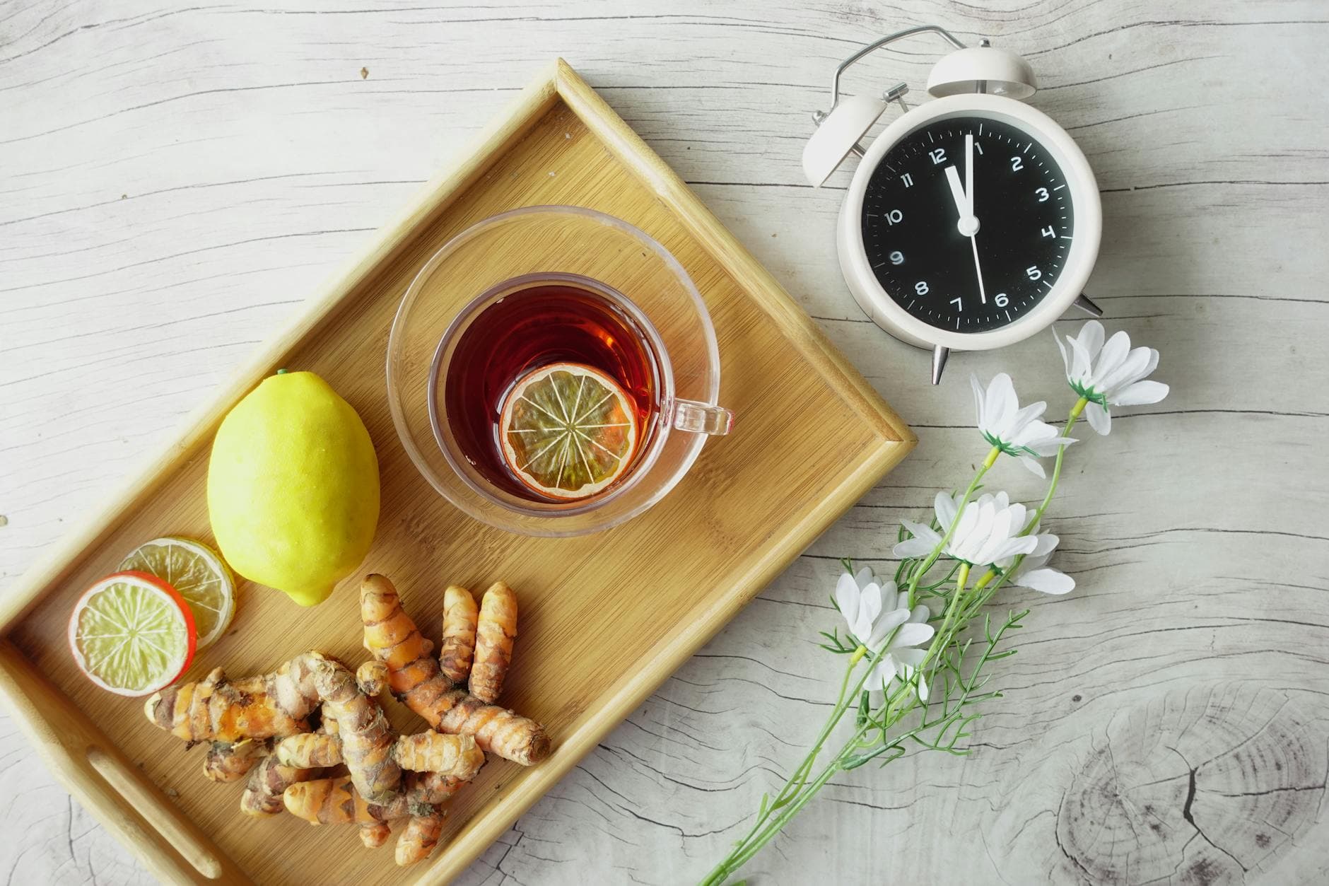 Overhead view of herbal tea with lemon, turmeric, and flowers on wooden tray. Healthy lifestyle concept. - spring detox tips