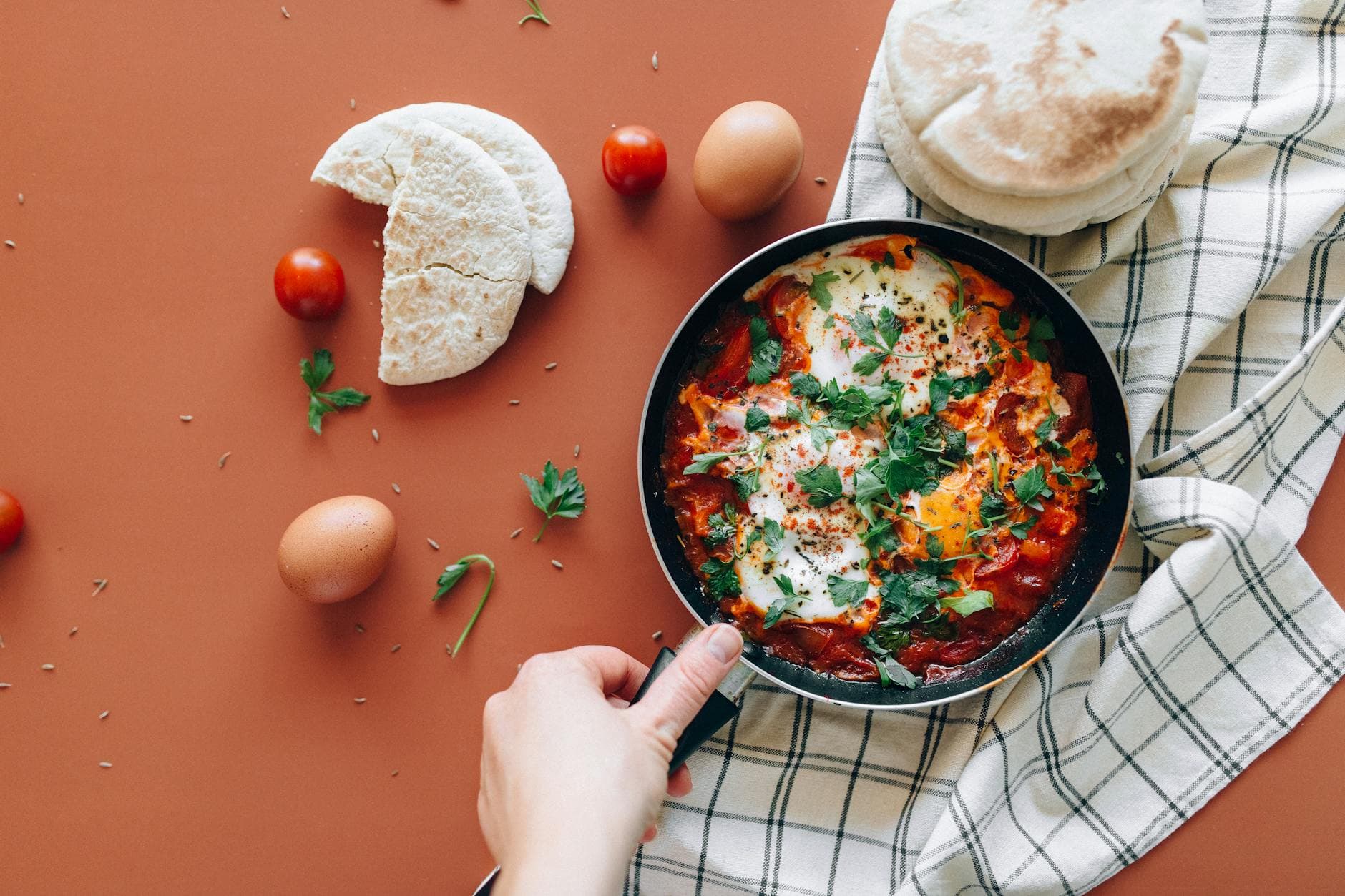 A vibrant shakshuka dish with pita, eggs, and fresh ingredients on a rustic backdrop. - weight watchers recipes