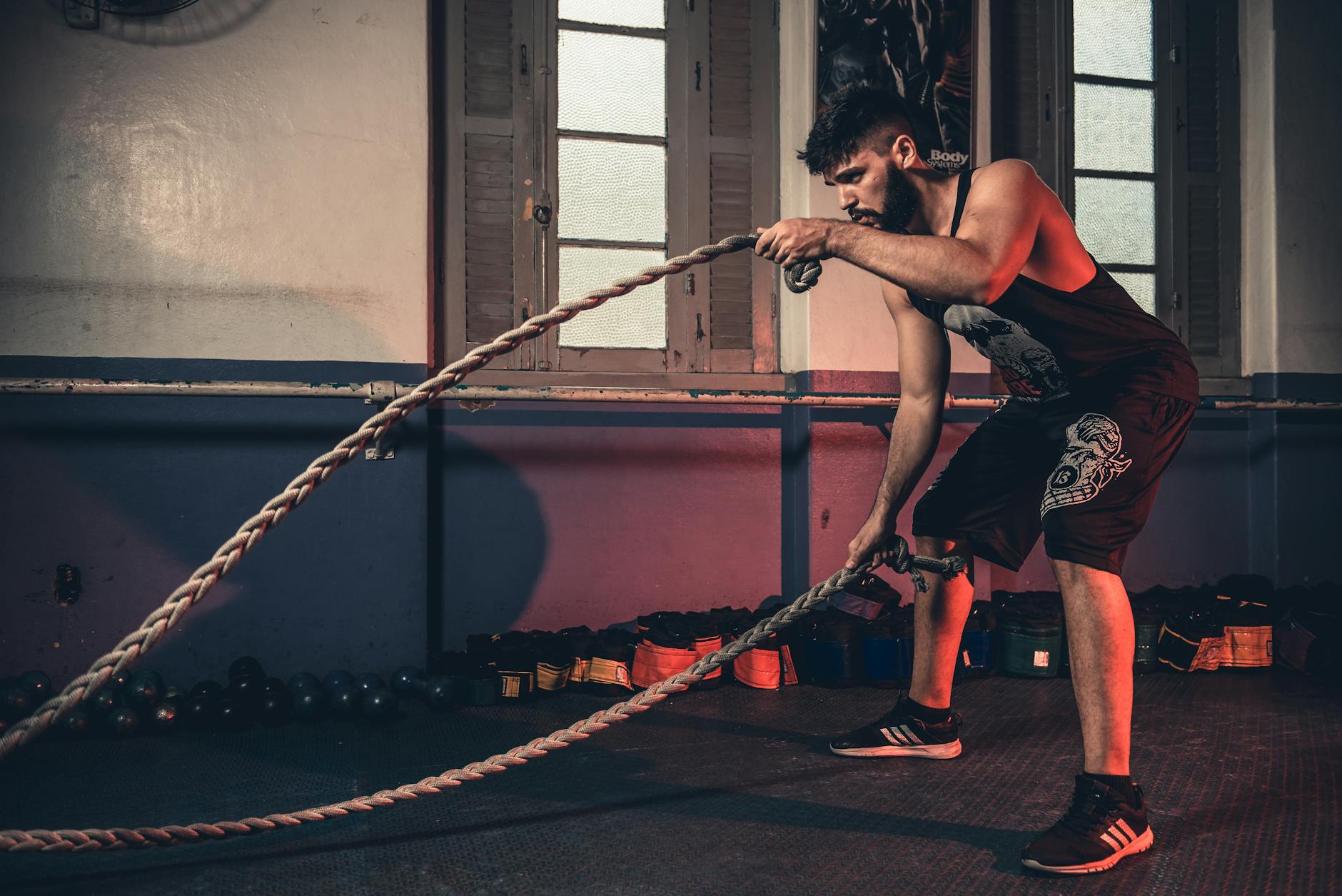 Man performing a challenging Crossfit rope exercise in an indoor gym setting. - best cardio exercises