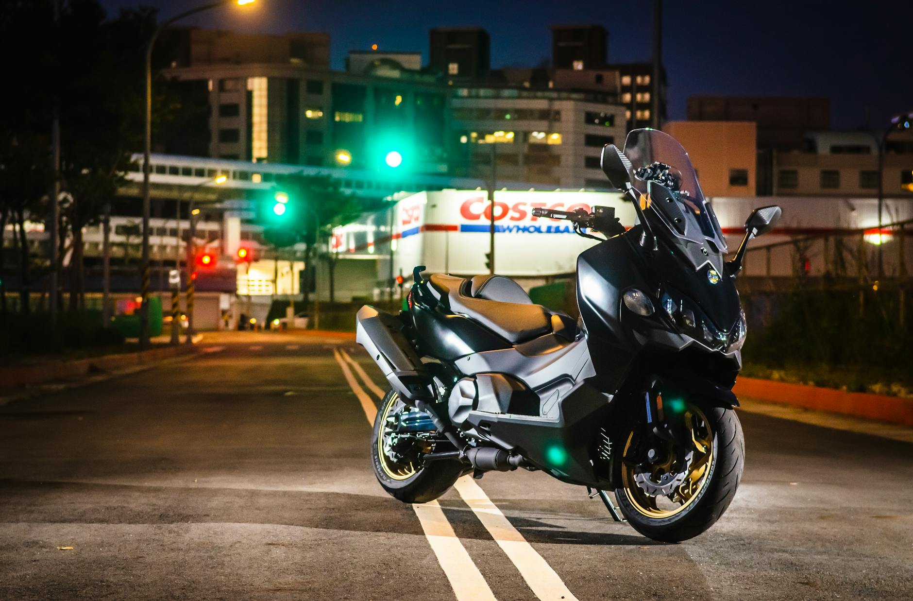 A sleek black motorcycle parked on a city street at night, illuminated by vibrant lights. - best costco healthy snacks