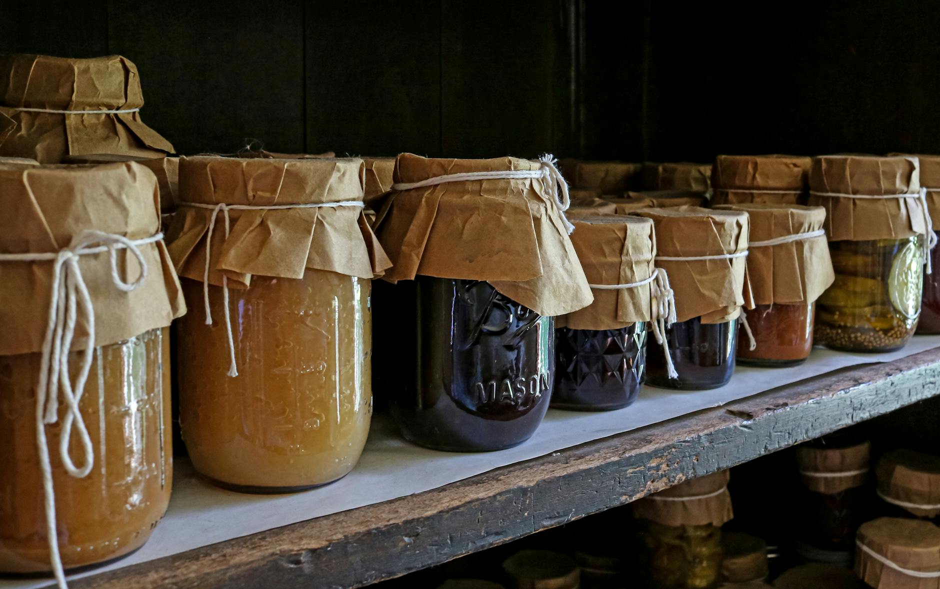 Assorted preserved foods in glass jars on a wooden shelf, showcasing traditional storage methods. - best gut health foods