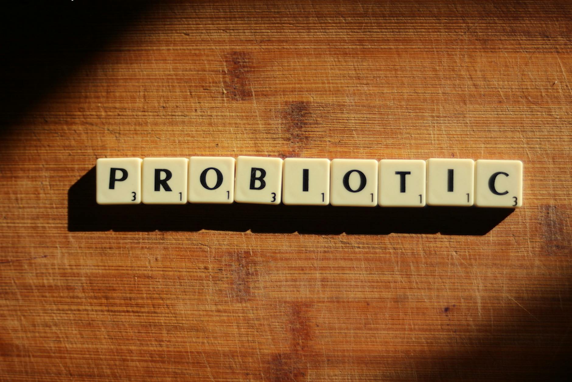 Close-up of the word 'probiotic' crafted from letter tiles on a wooden surface. - best gut health foods