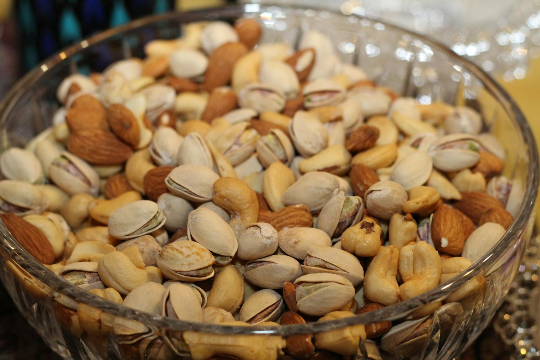 A close-up view of a glass bowl filled with various mixed nuts, including almonds, cashews, and pistachios. - best plant based protein powder