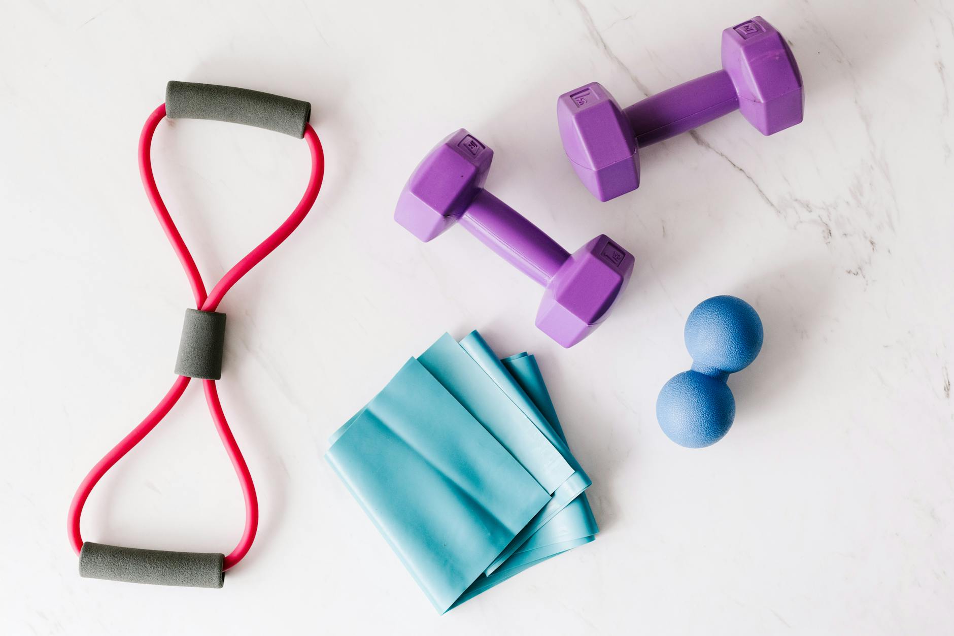 Colorful home workout equipment, including dumbbells and resistance bands, on a marble surface. - best resistance band workout