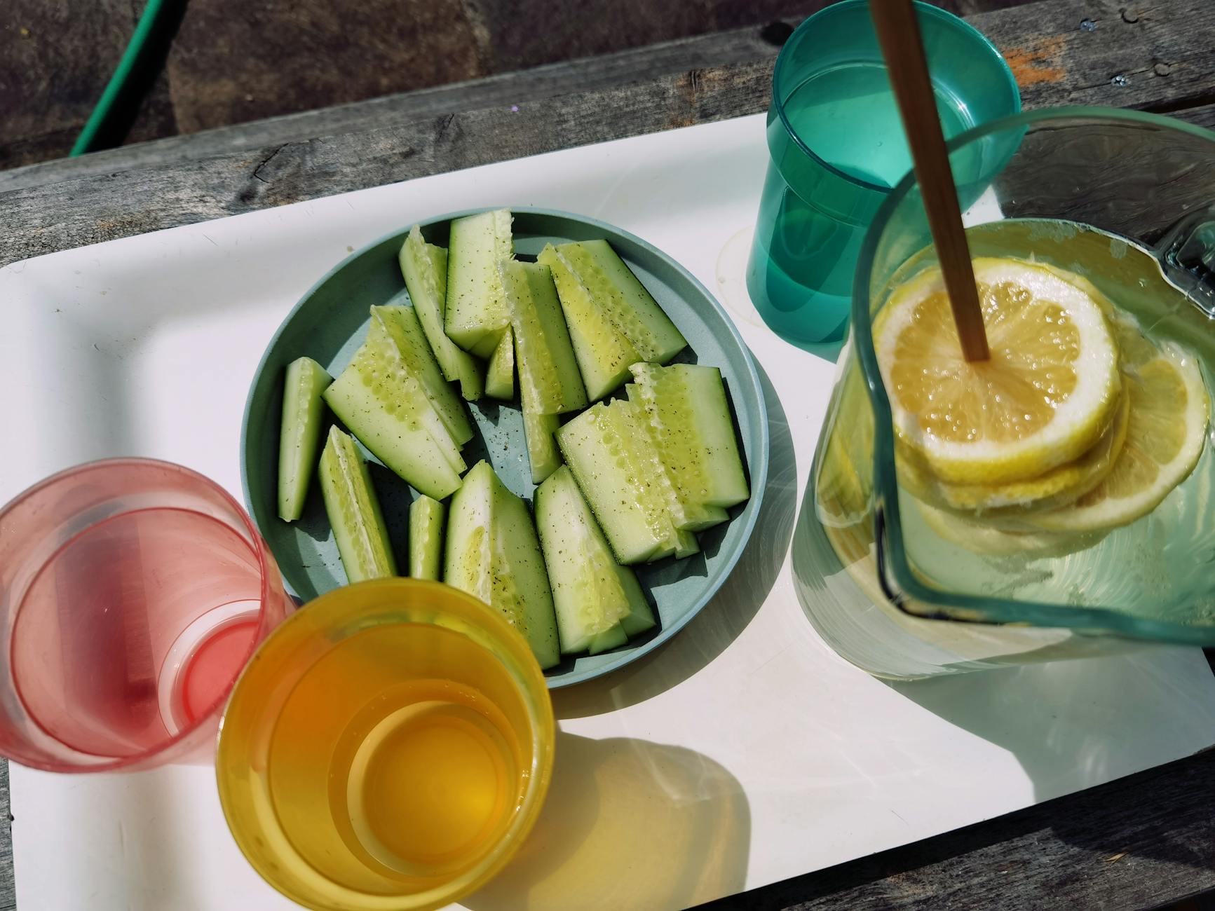 Top view of cucumber sticks and lemon water outdoors. Perfect for a refreshing summer snack. - cucumber lemon detox water