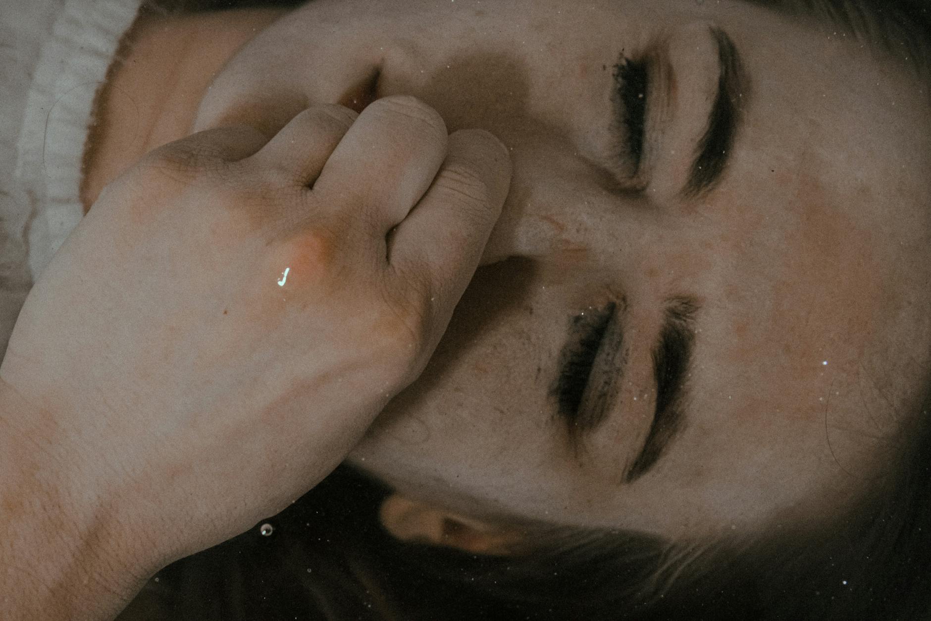 Top view of female with closed eyes lying underwater in bathtub and pinching nose while holding breath at home in bathroom - deep breathing for anxiety