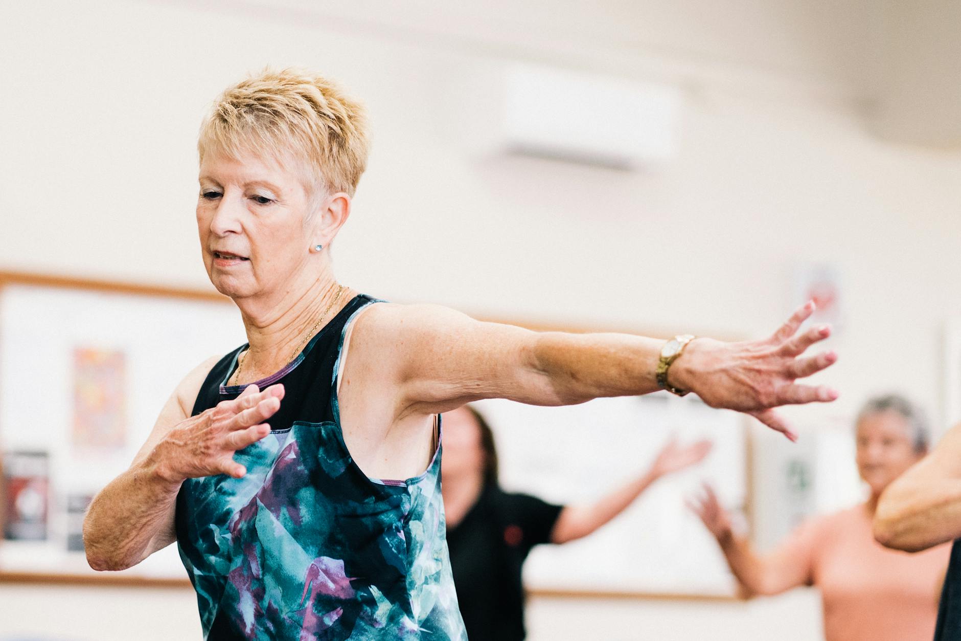 Senior woman participating in a lively fitness class indoors, embracing positive aging. - healthy aging tips seniors