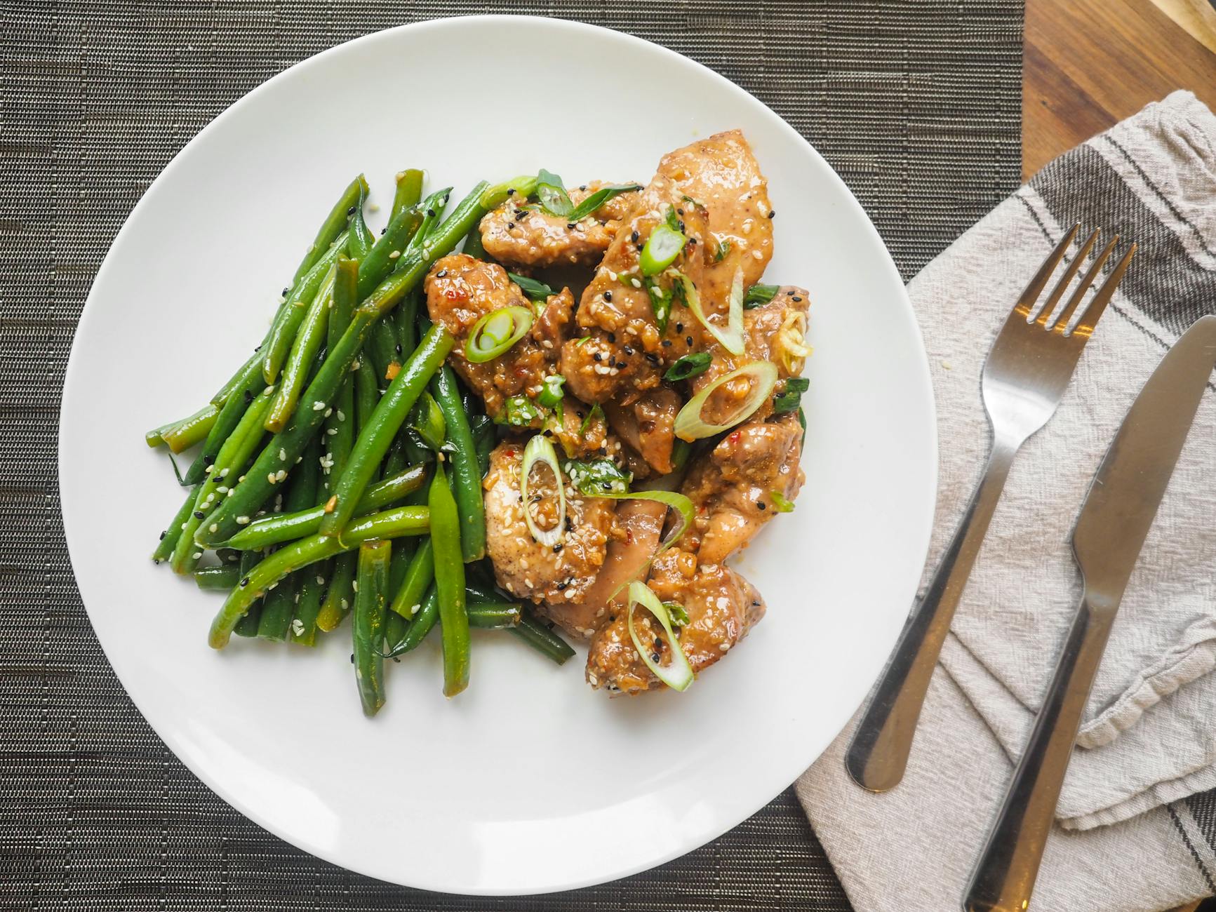 A delicious serving of sesame chicken with fresh green beans on a white plate, perfect for dinner. - healthy dinner recipes