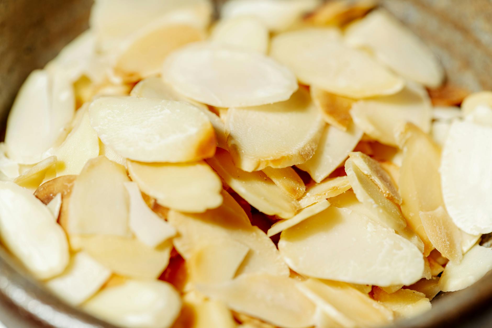 Macro shot of fresh sliced almonds in a rustic bowl, ideal for food photography. - high protein foods