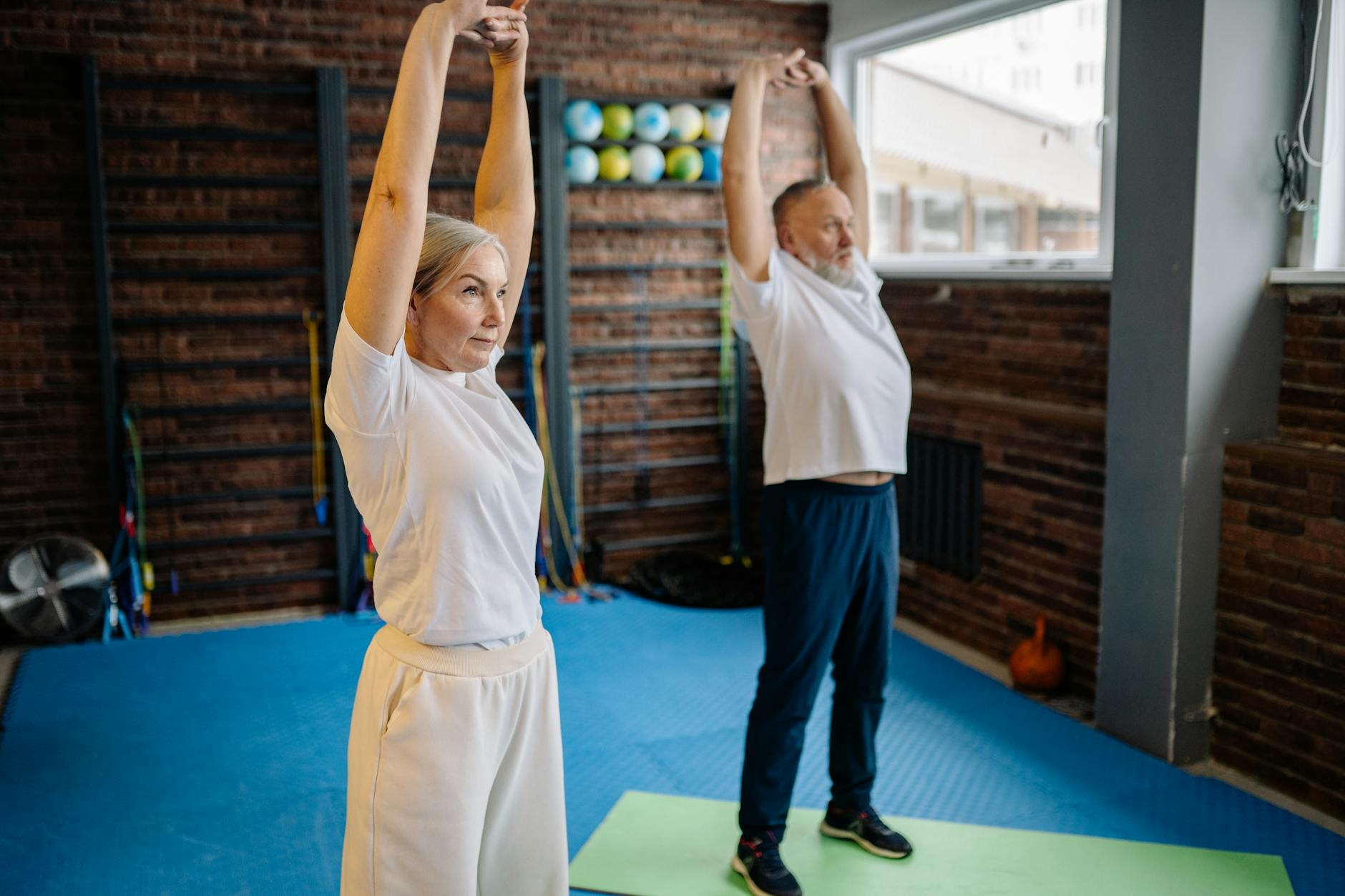 Active senior couple engaging in stretching exercises indoors for fitness and health. - hip mobility exercises