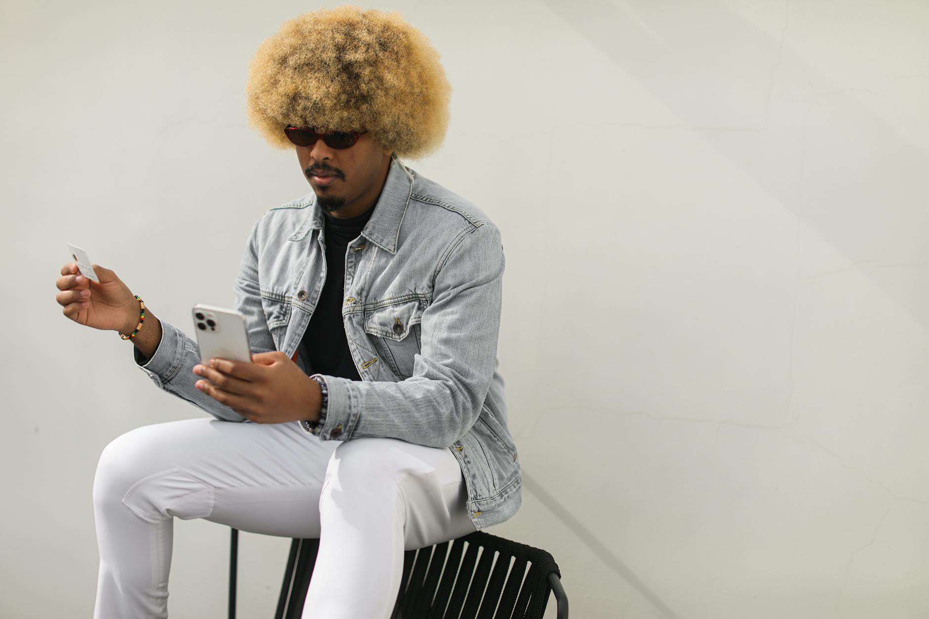 Stylish man with afro hairstyle using smartphone and credit card for online shopping. - hip mobility exercises