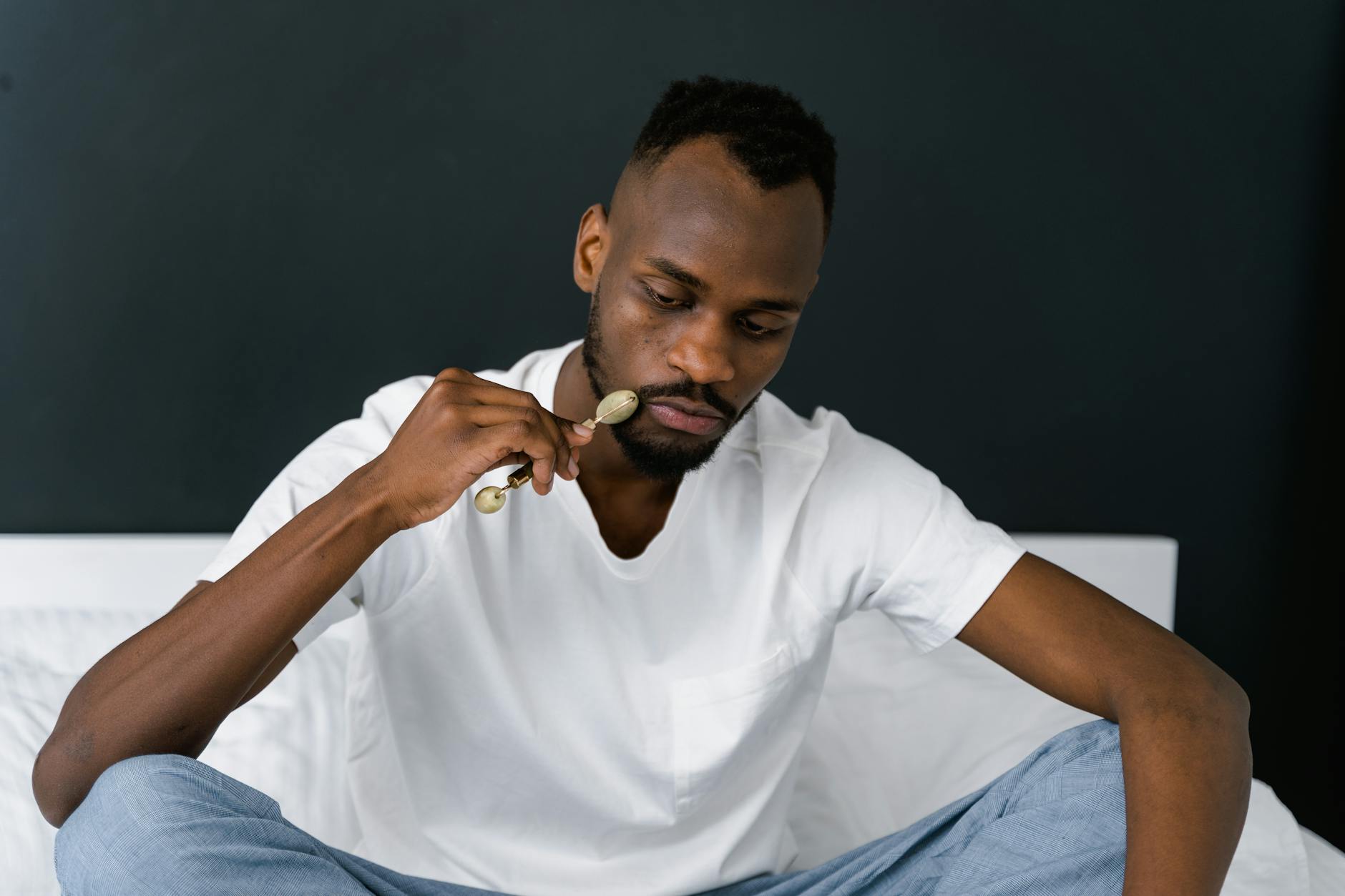 A man using a jade roller for facial care, promoting skincare routines. - men's natural skincare