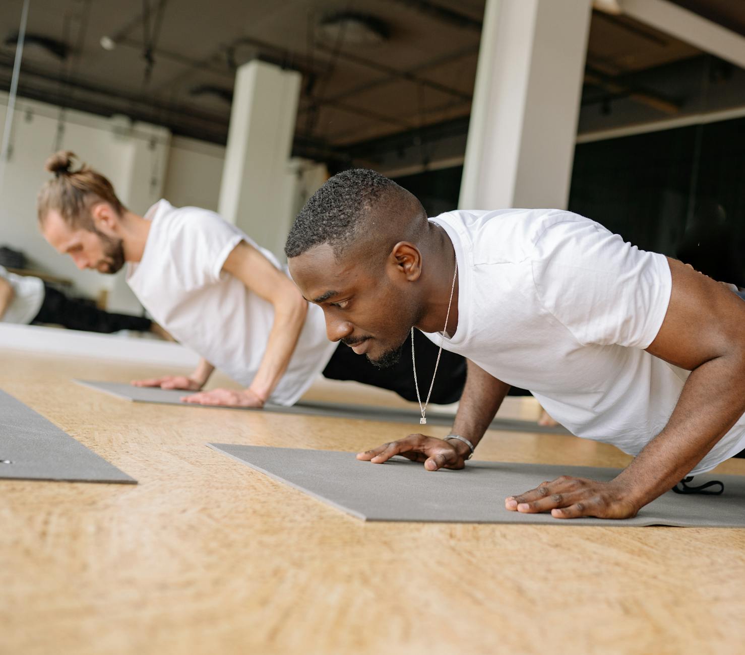 Two adult men working out indoors, focusing on push-ups for strength training. - men's workout routine