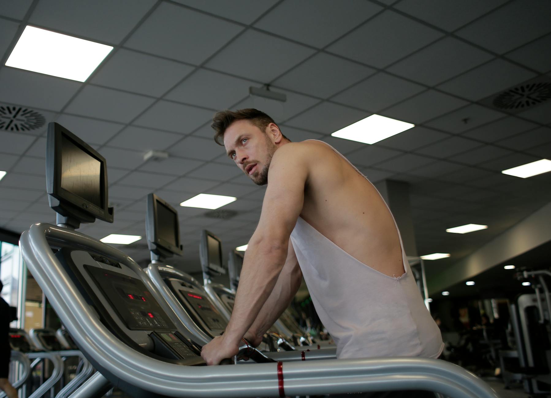 A focused man exercising on a treadmill in a modern gym setting, showcasing dedication and fitness. - men's workout routine