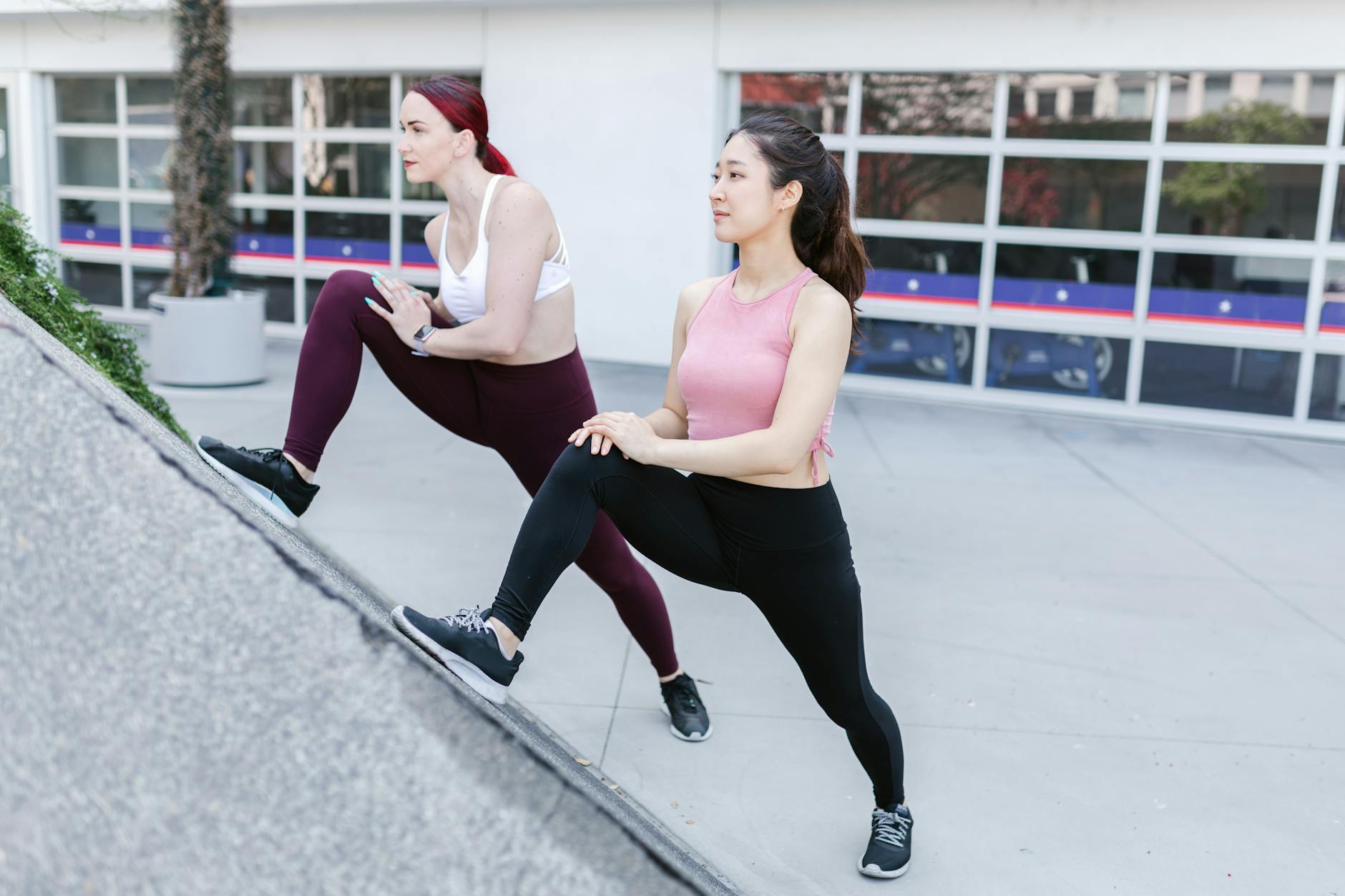 Two women in activewear stretching outdoors on a sunny day. - morning workouts for women