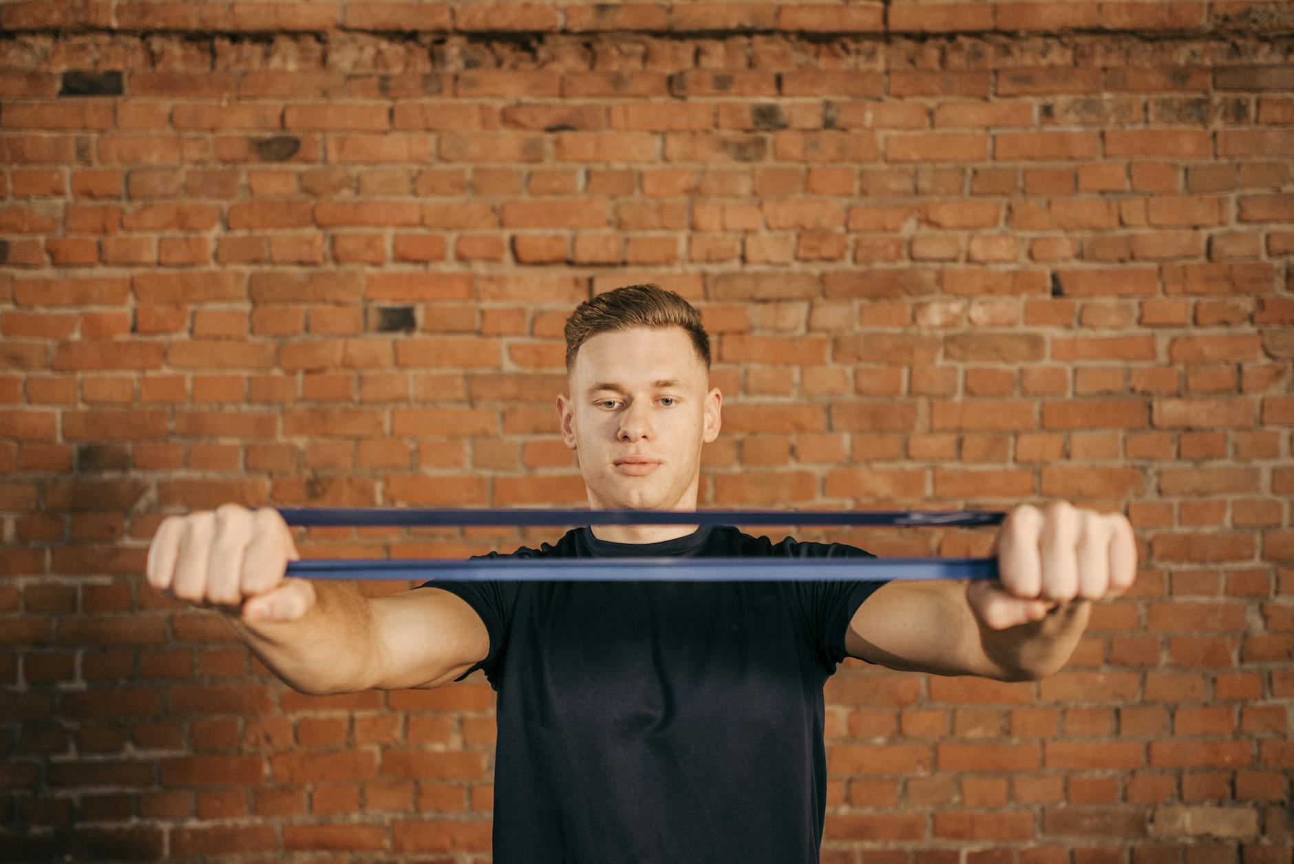 Man using resistance band against brick wall for fitness exercise. - resistance band exercises