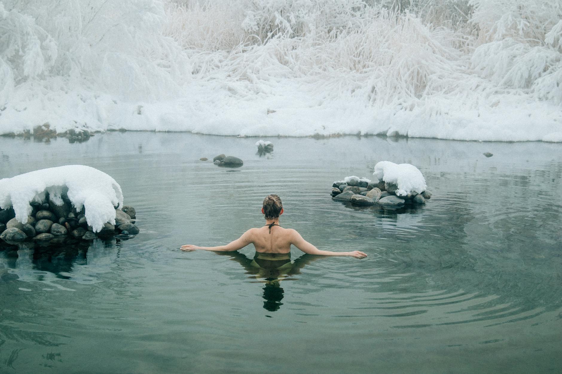 A young woman enjoying a swim in a tranquil winter lake surrounded by snow. - swimming benefits for men