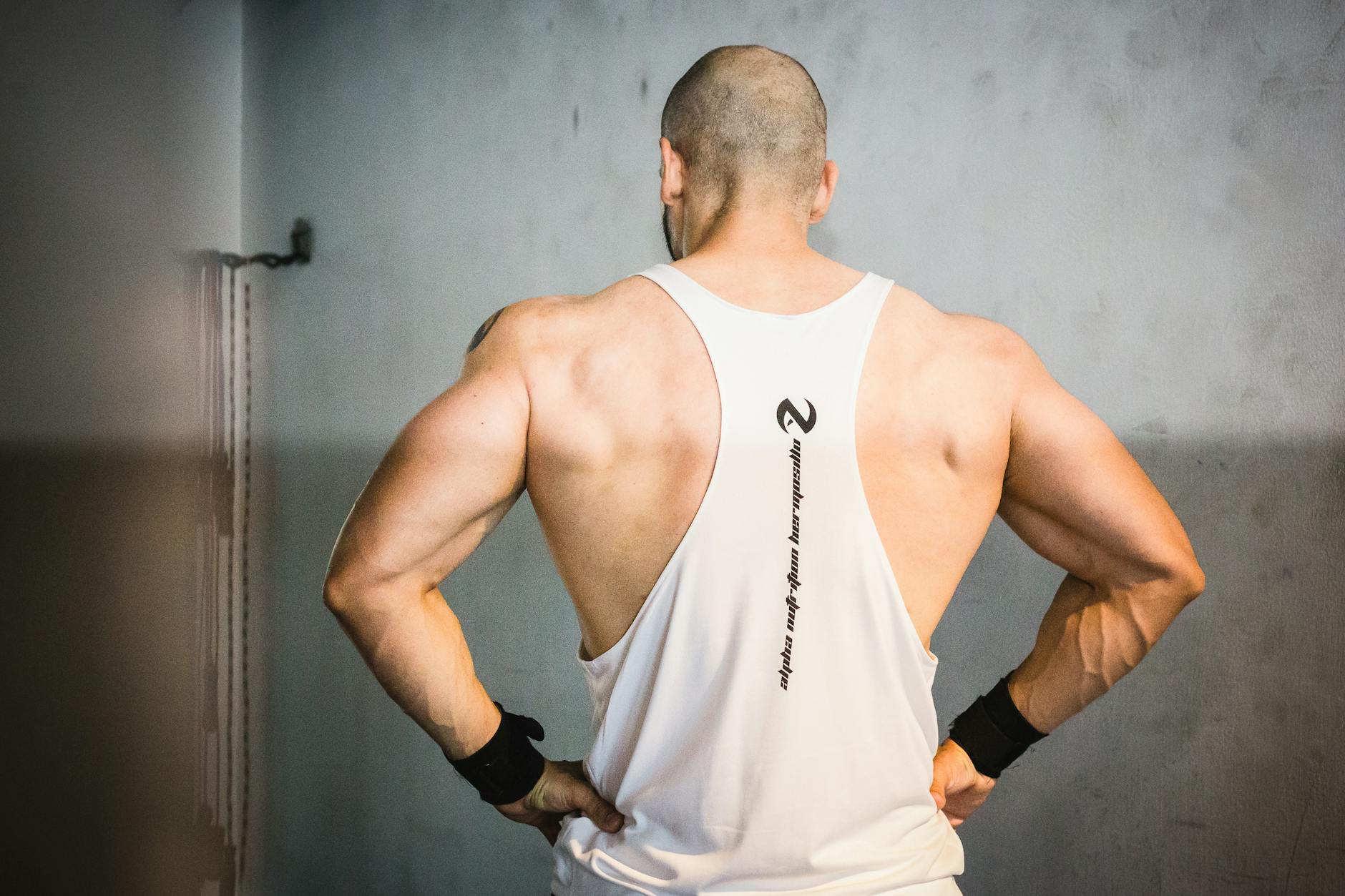 A muscular man from behind showcasing strength and fitness in a gym setting. - upper back posture exercises