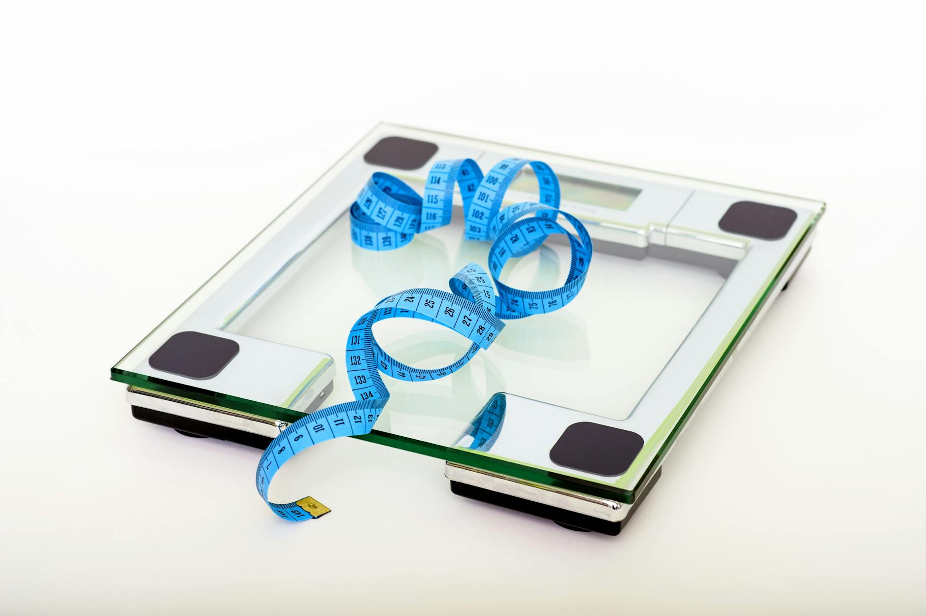 A digital glass weighing scale with a blue measuring tape, symbolizing weight management. - walking for weight loss