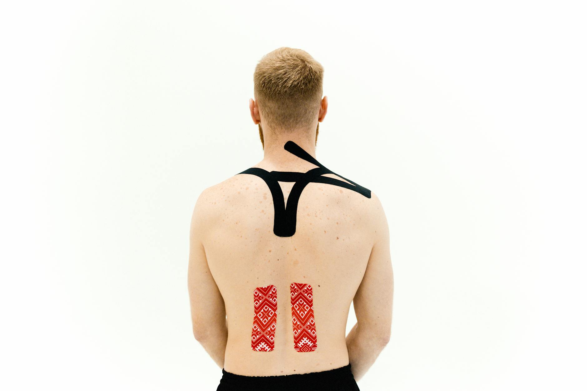 Man with kinesio tape on his back for muscle support and pain relief. Medical treatment with white background. - arthritis back pain