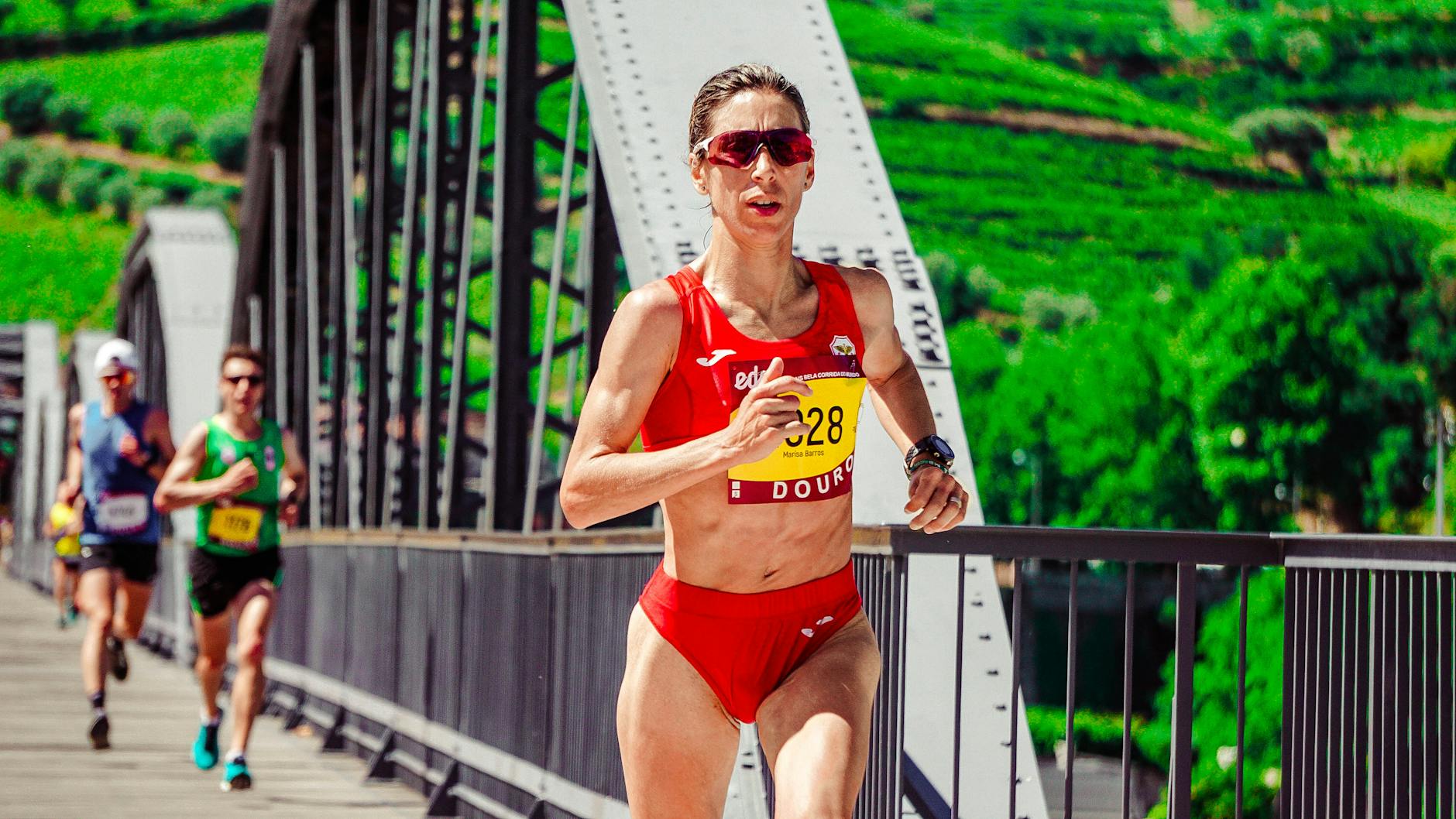 Focused female athlete competing in a marathon on a scenic bridge. Outdoor sports action. - beginner running plan