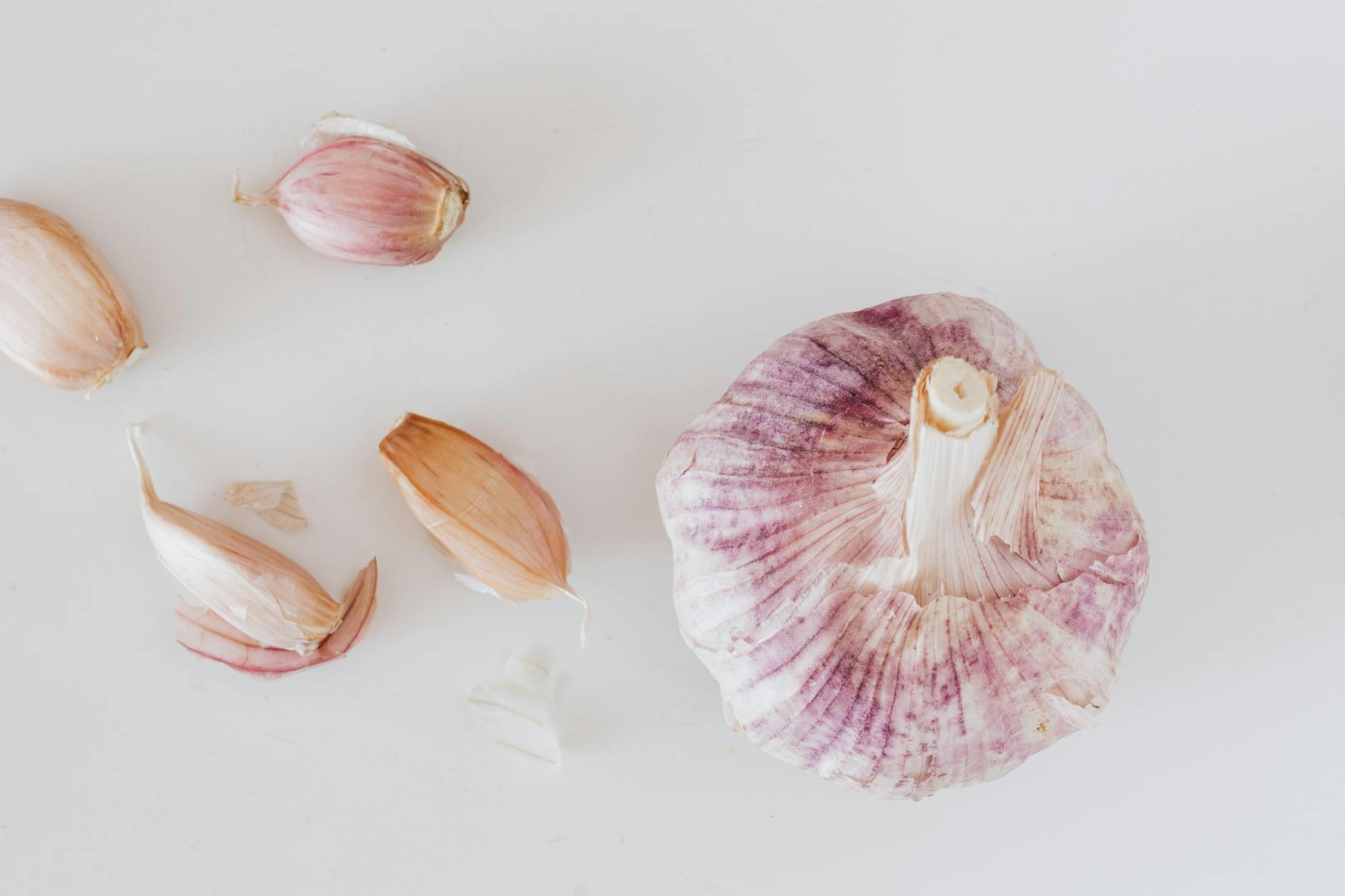 From above closeup of big whole garlic and set of cloves placed on white surface - best anti inflammatory foods