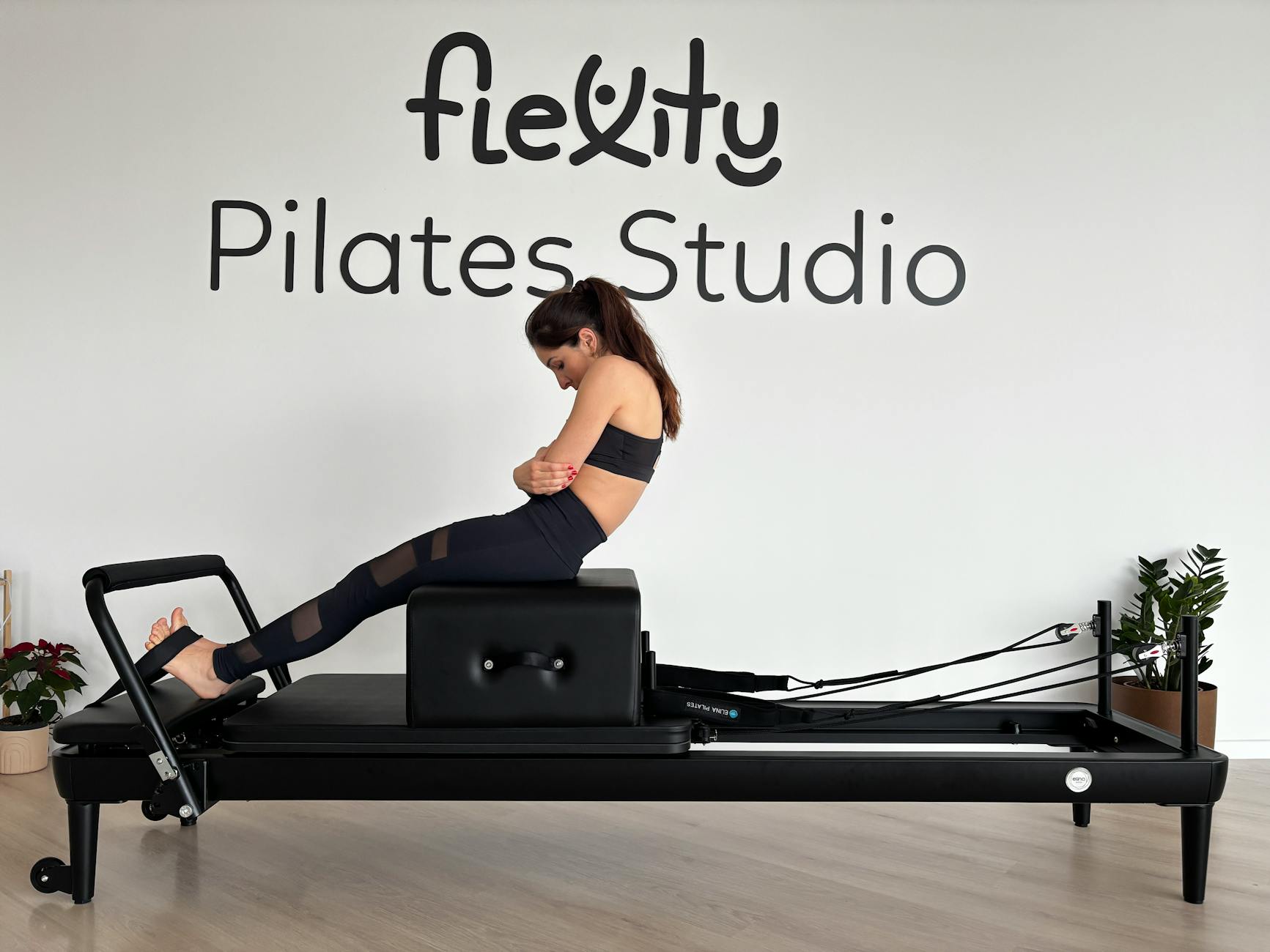 A woman is doing a Pilates workout on a reformer machine at a Pilates studio. - best pilates exercises
