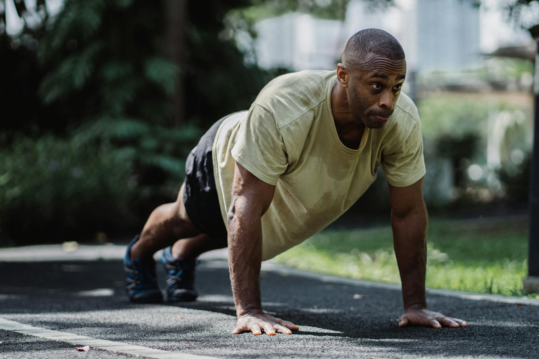 African American man exercising in a park, focusing on fitness and healthy living with outdoor push-ups. - bodyweight cardio