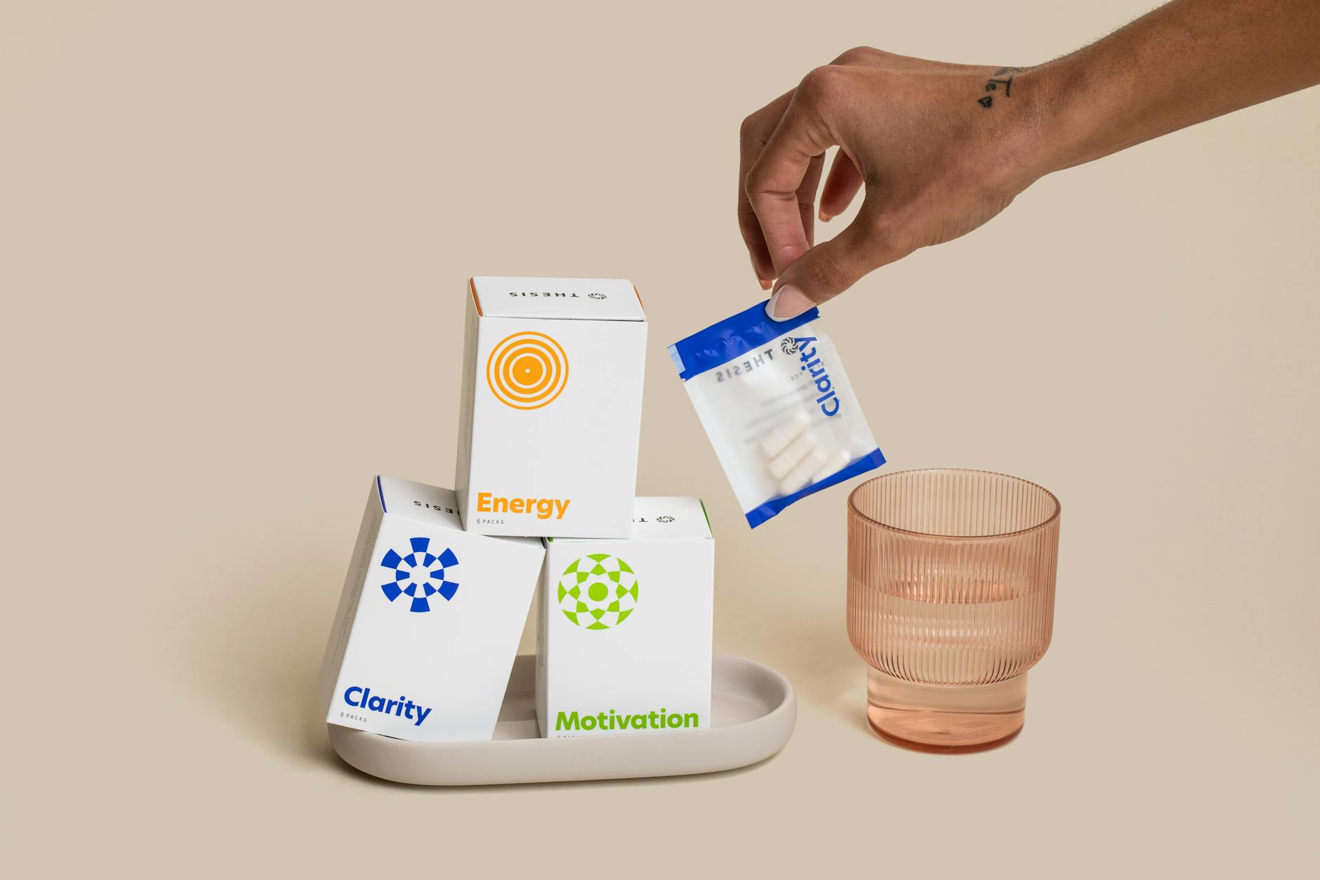 A close-up of dietary supplements for clarity, motivation, and energy with packaging and a hand reaching for a pouch. - boost energy naturally
