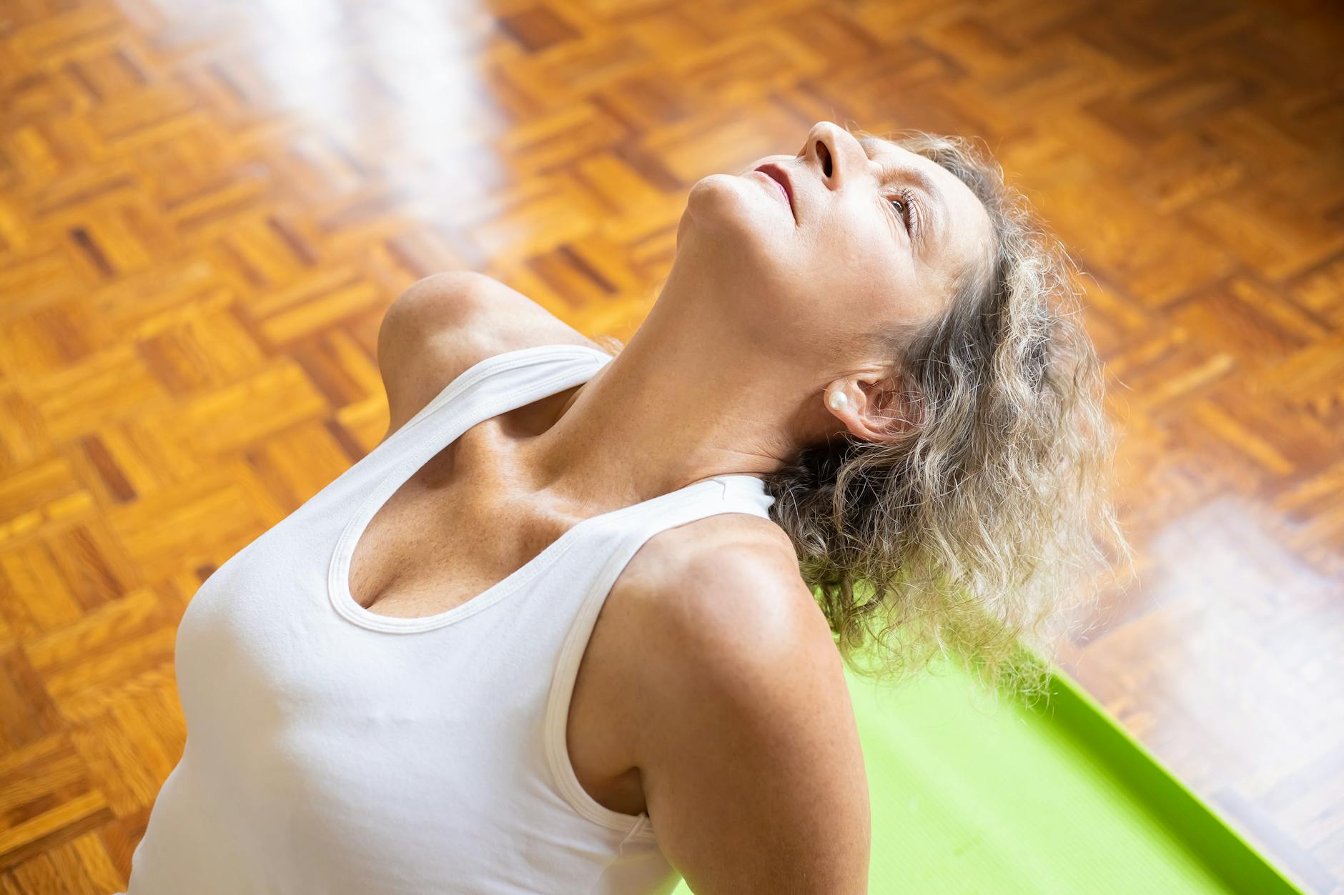 An elderly woman stretching on a yoga mat, promoting fitness and a healthy lifestyle. - breathing exercises stress