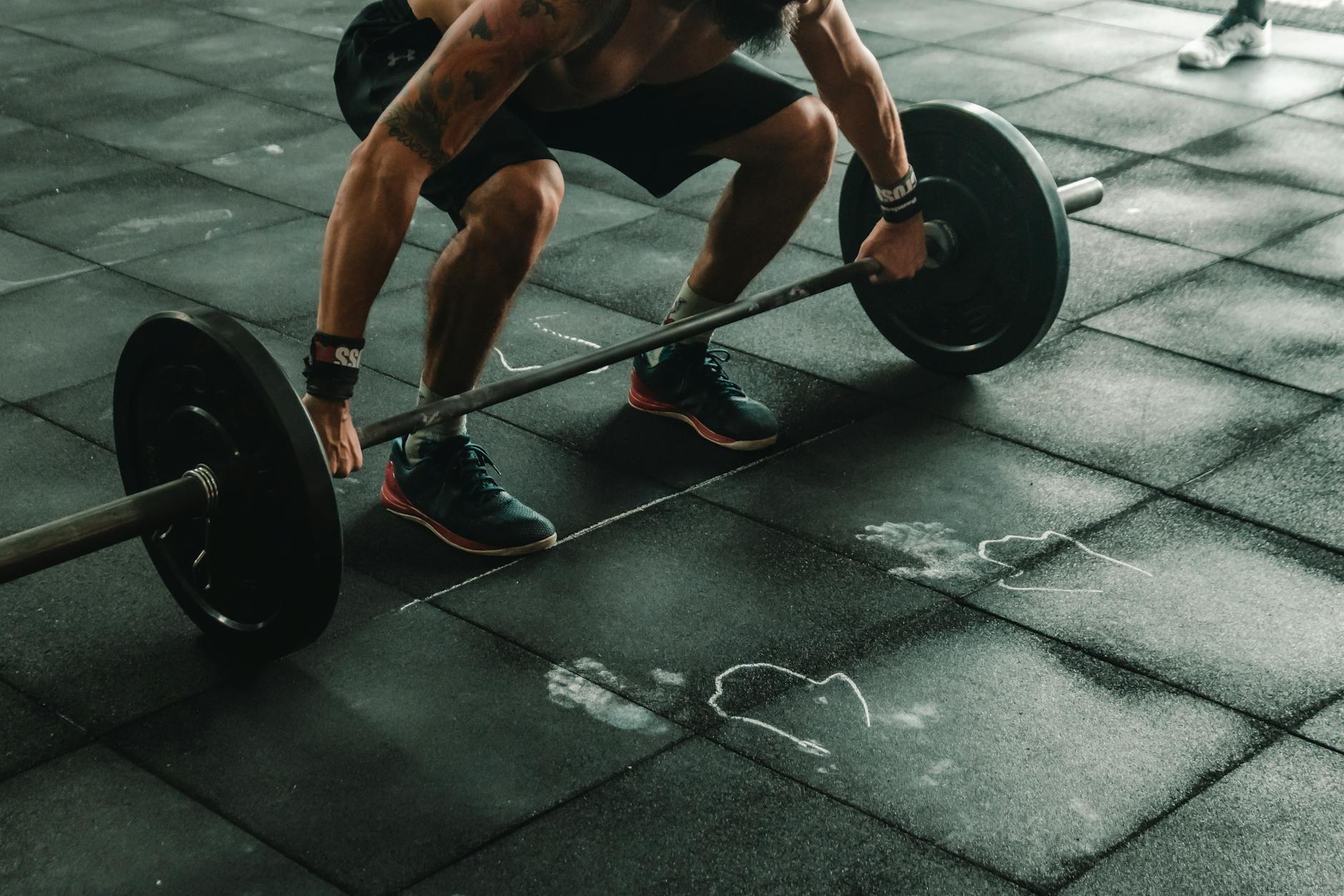 A muscular man in a gym preparing to lift a heavy barbell, showcasing strength and fitness. - crossfit workout plan