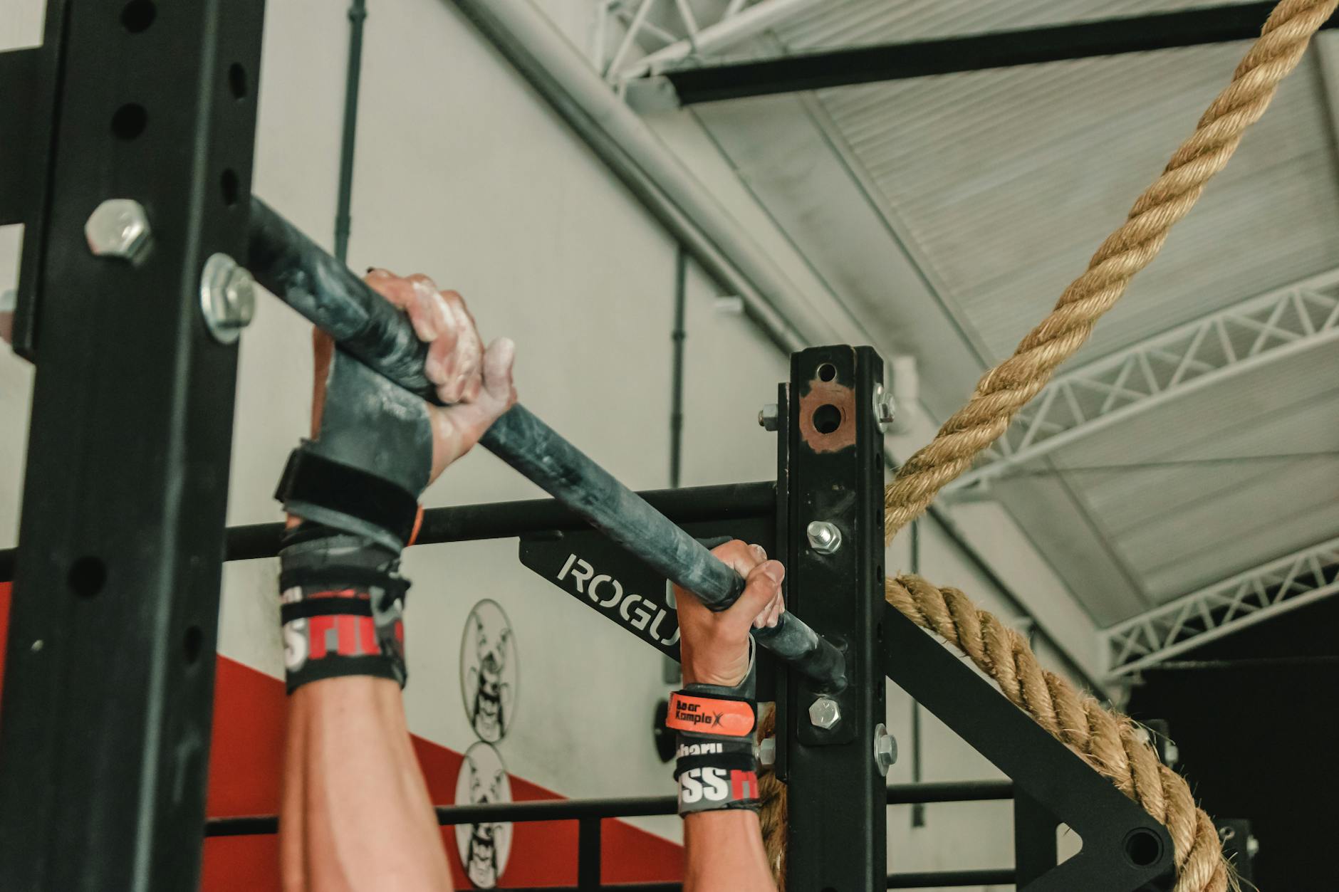 Close-up of hands gripping pull-up bar during an intense gym workout session. - crossfit workout plan