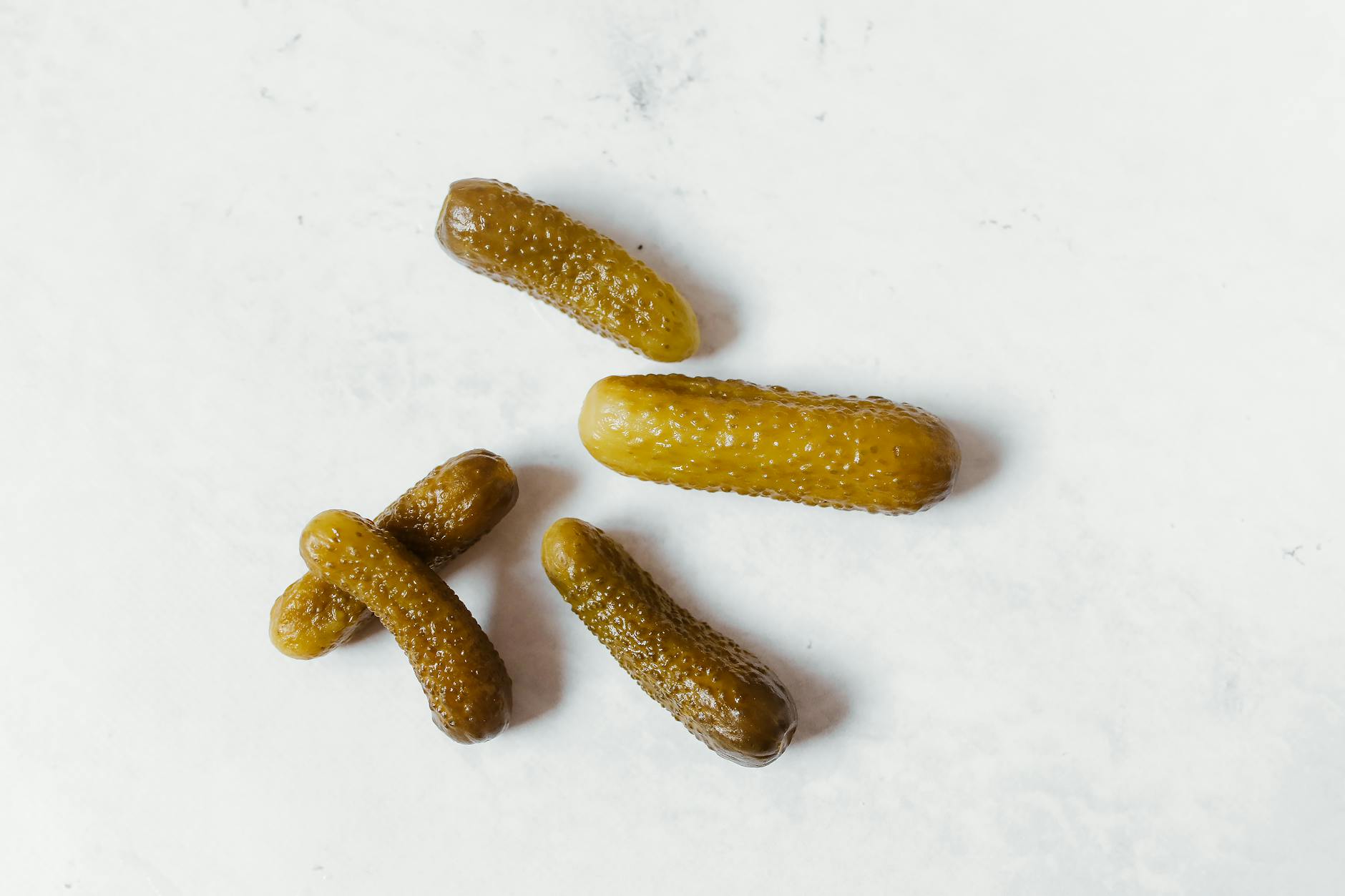 Five pickled cucumbers arranged on a clean white background, emphasizing texture and color. - cucumber water benefits