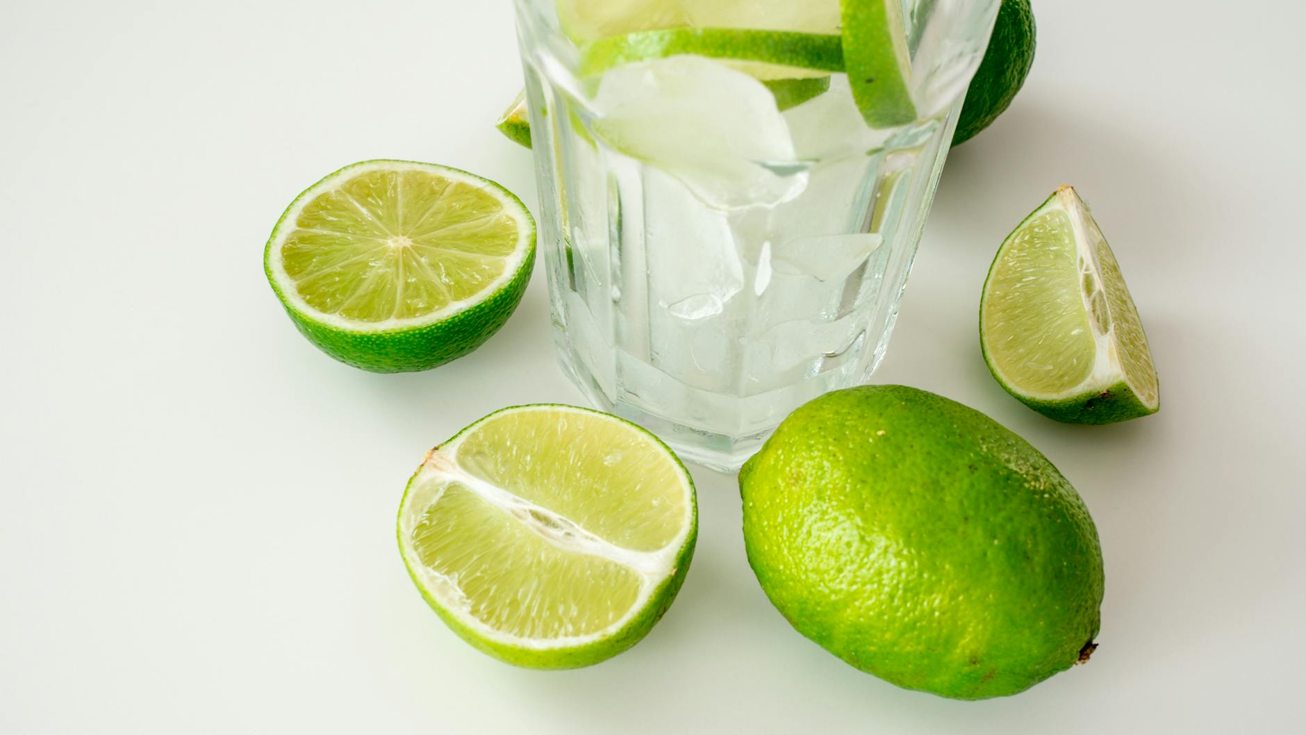 A crisp and refreshing glass of ice water with sliced limes on a bright surface. - how to detox