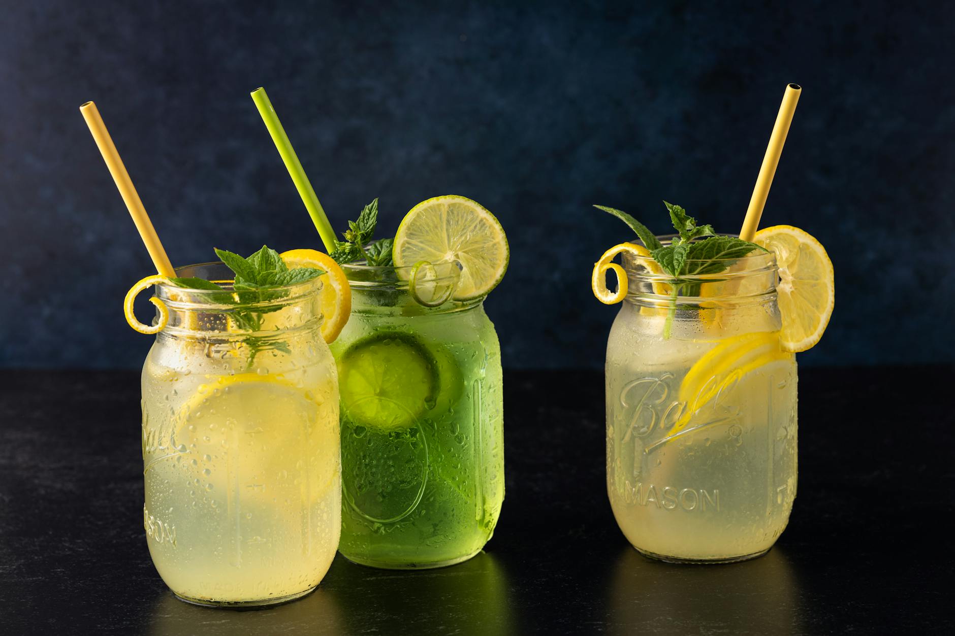 Three mason jars filled with lemon and lime refreshment garnished with mint. - detox drink recipes