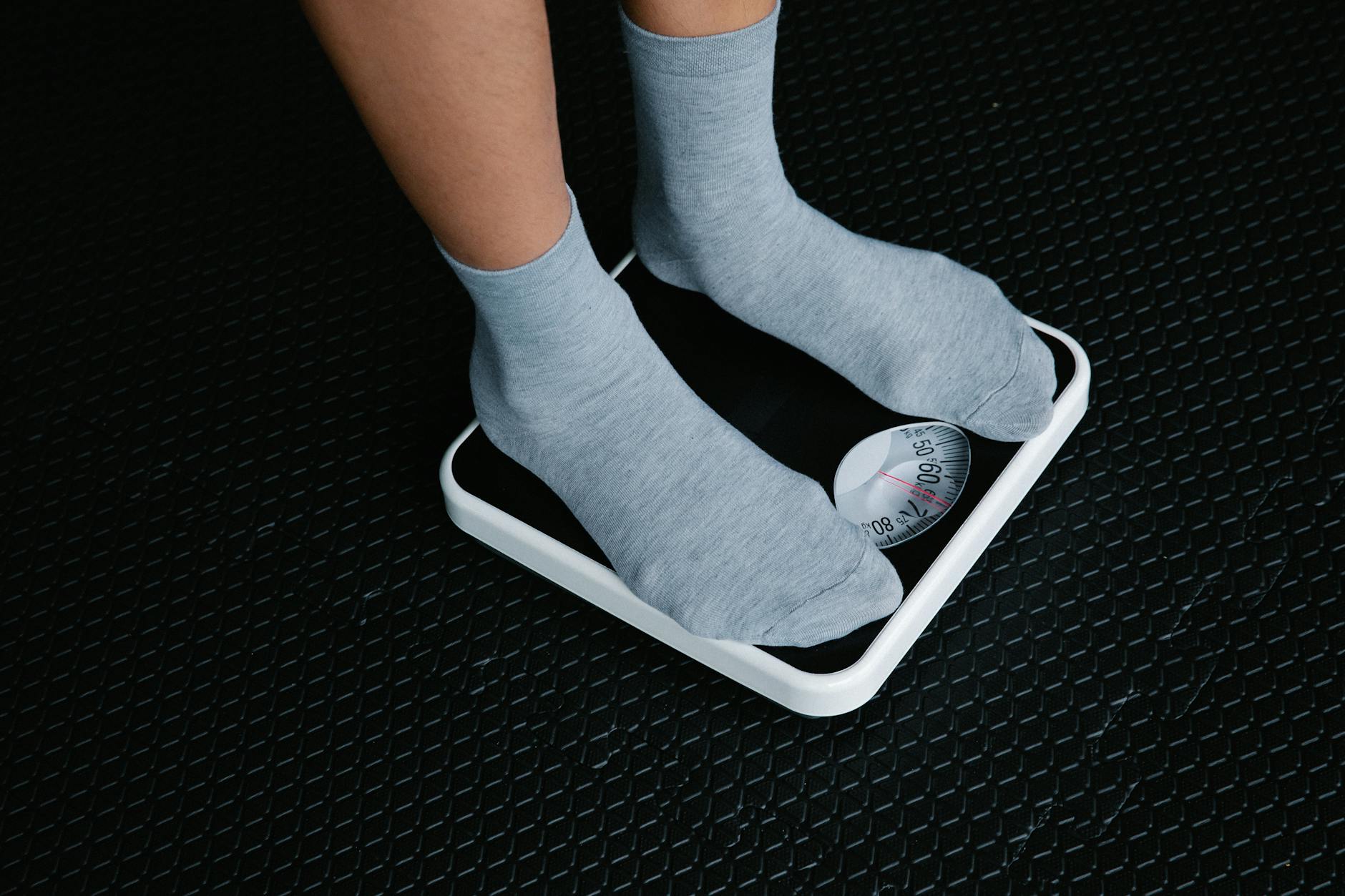 Close-up of feet in socks standing on a scale, focusing on weight measurement. - easy weight loss