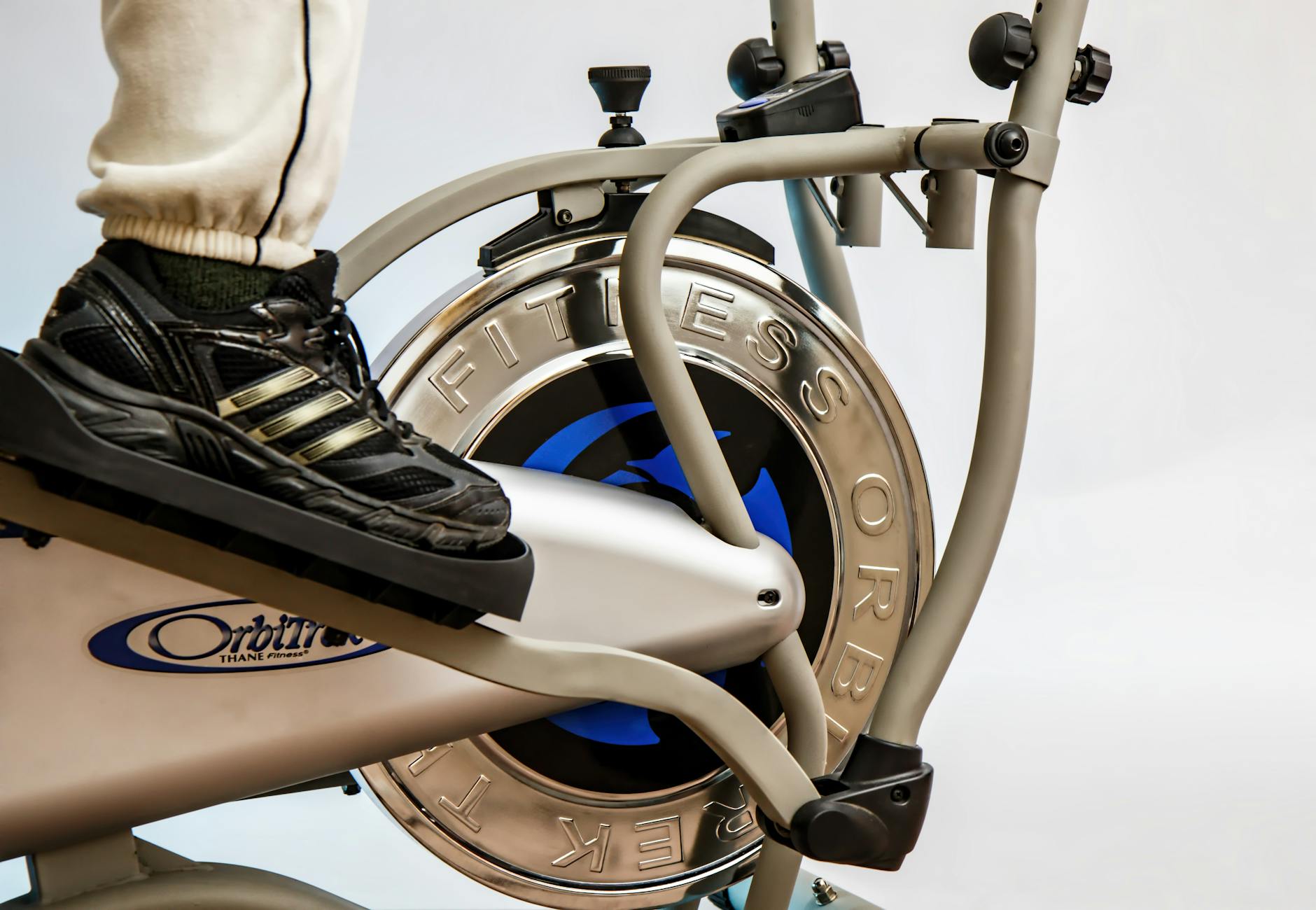 Foot on pedal of elliptical trainer showcasing fitness equipment and footwear close-up. - no equipment cardio workout