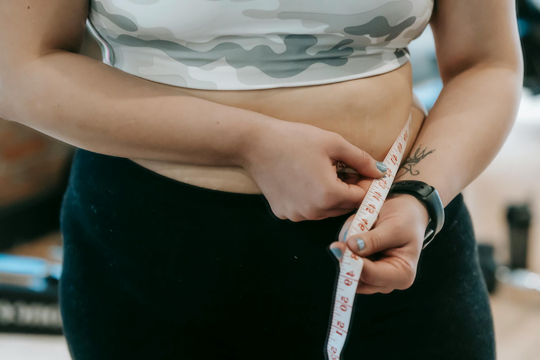 Close-up of a woman's waist being measured with a tape. Fitness and health concept. - extreme weight loss