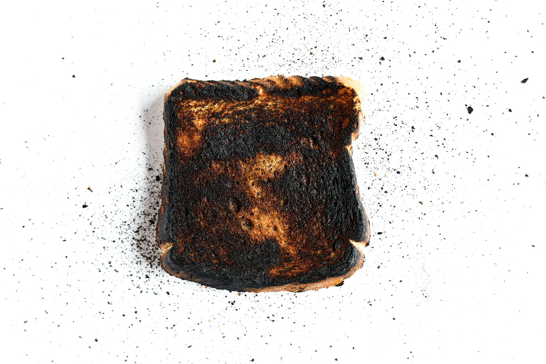 A piece of burnt toast on a white surface, perfect for culinary mishap concepts. - fat burning foods
