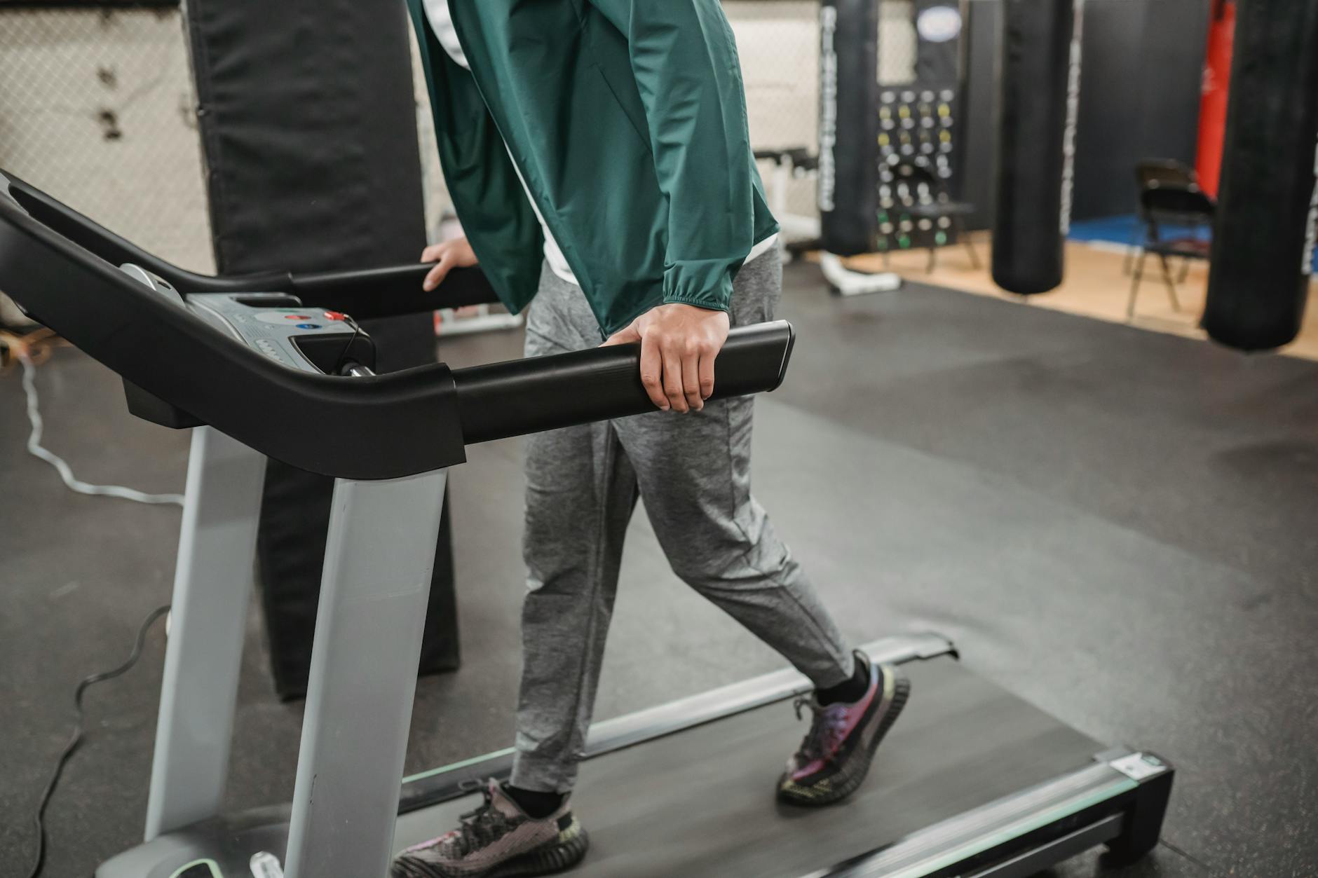 Crop anonymous male walking on contemporary treadmill in modern sport club with gym equipment - fat burning treadmill